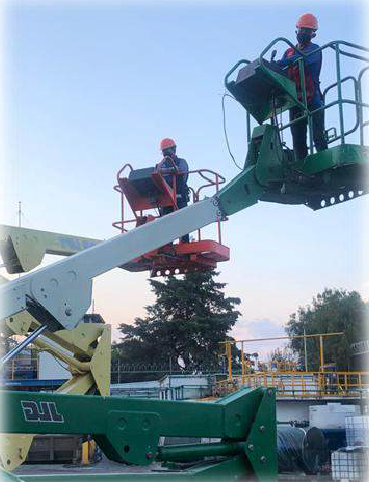Trabajador de construcción con casco amarillo y mascarilla en una fábrica.
