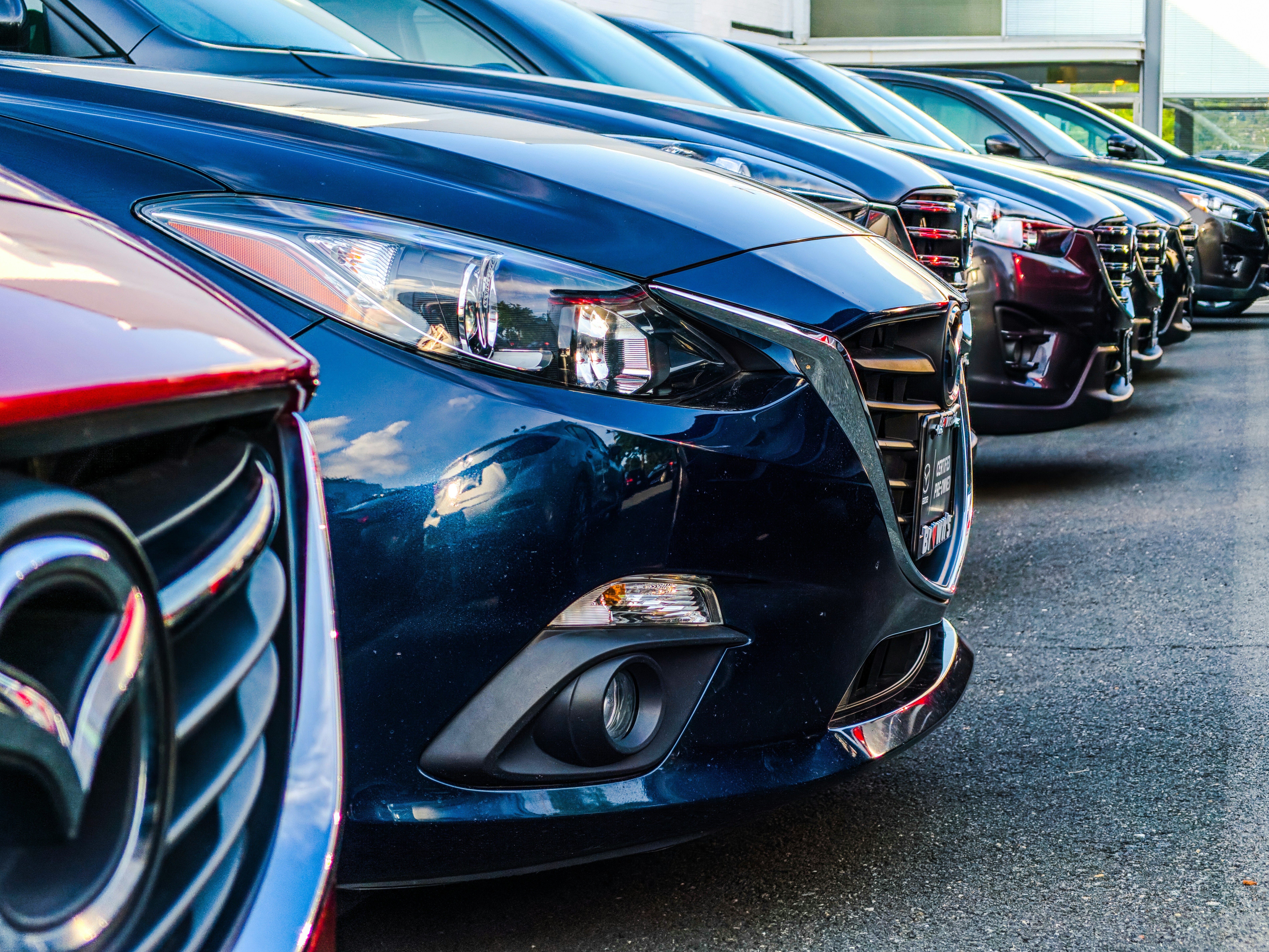 Row of modern cars parked in a dealership lot, highlighting sleek designs and polished exteriors.