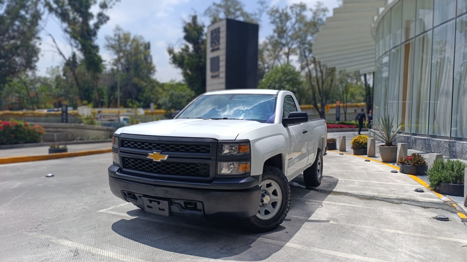 Coches deportivos amarillos en un taller mecánico moderno, con luces brillantes y equipo de elevación.