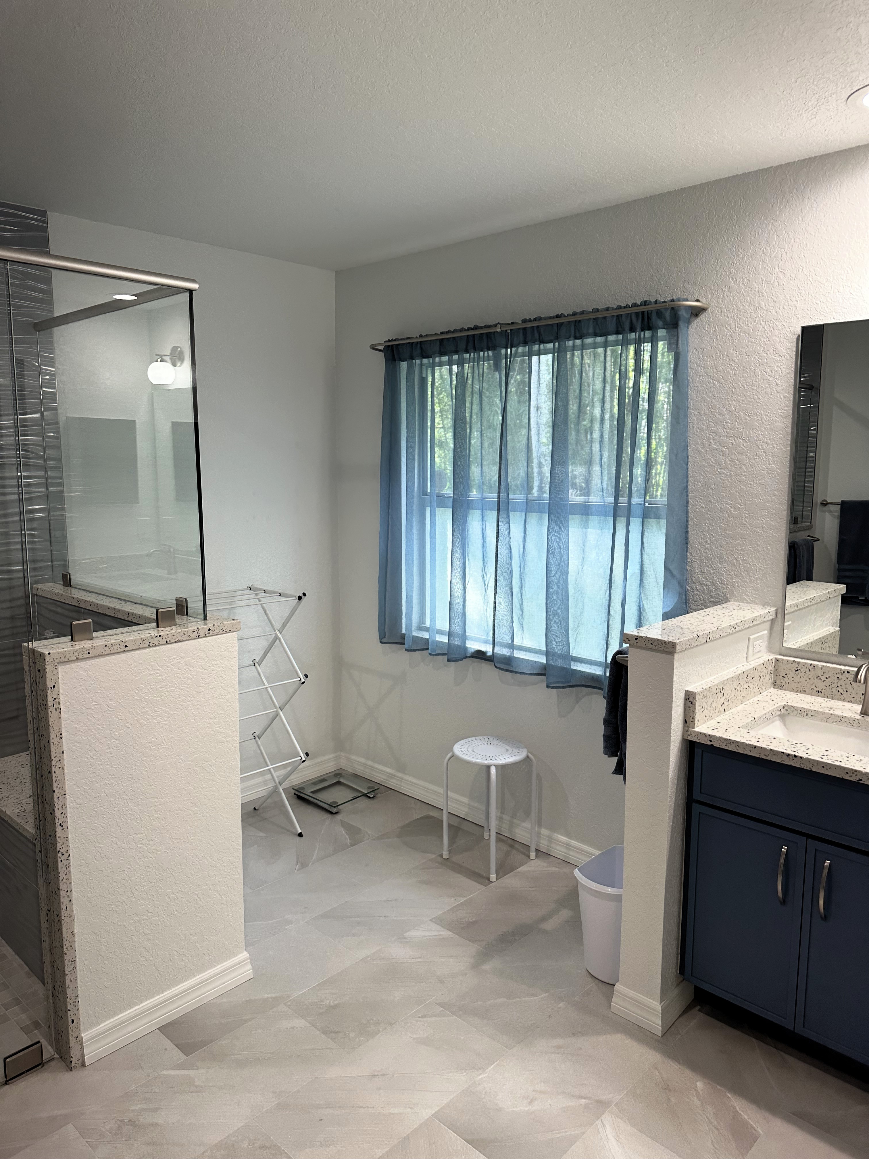 The 12x24 soft grey porcelain tile flooring transforms the bathroom into a serene, spa-like retreat, creating a calming foundation that enhances the overall tranquility of the space.