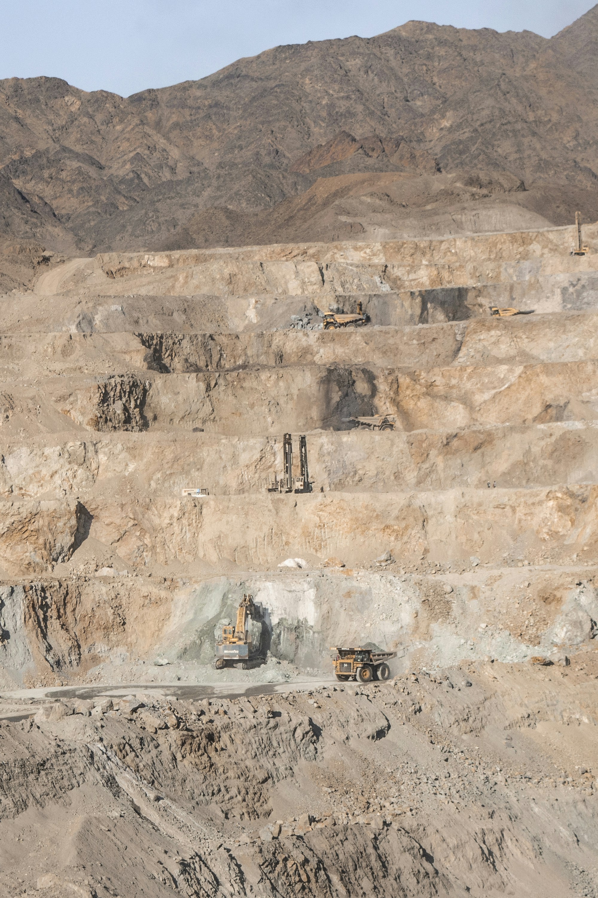 Vista aérea de obra de construcción de carretera con excavadoras, estructuras de hormigón y taludes en terreno montañoso
