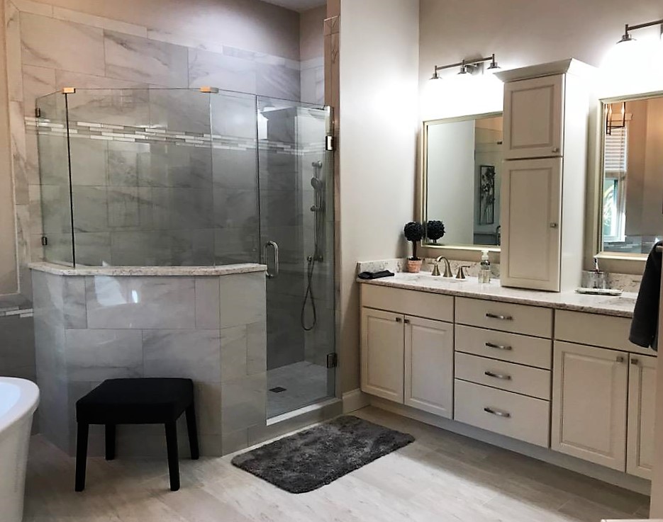 Double vanity featuring framed mirrors and lighting with additional cabinet
 storage between the dual sinks.