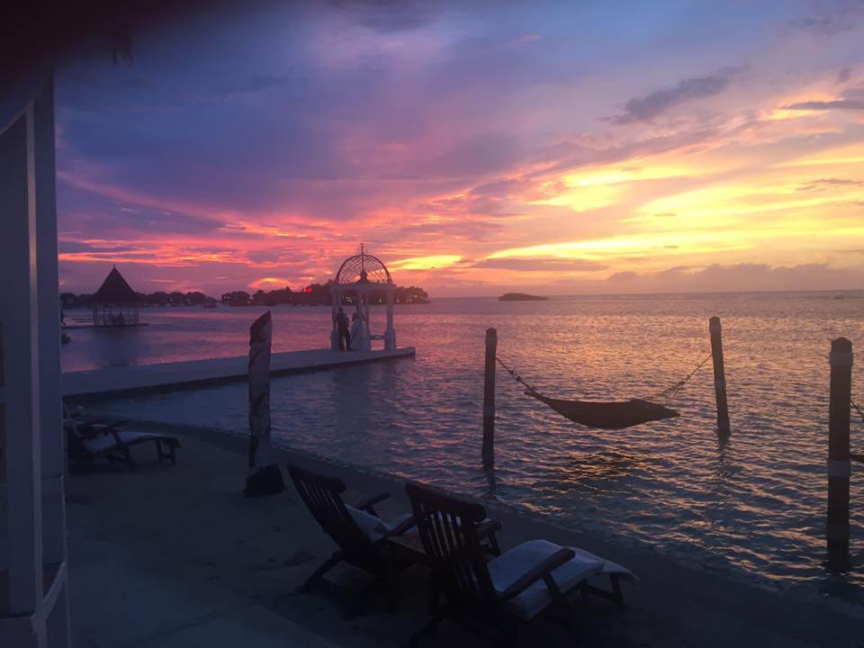 A newlywed couple looking out at the sunset at the end of a pier.