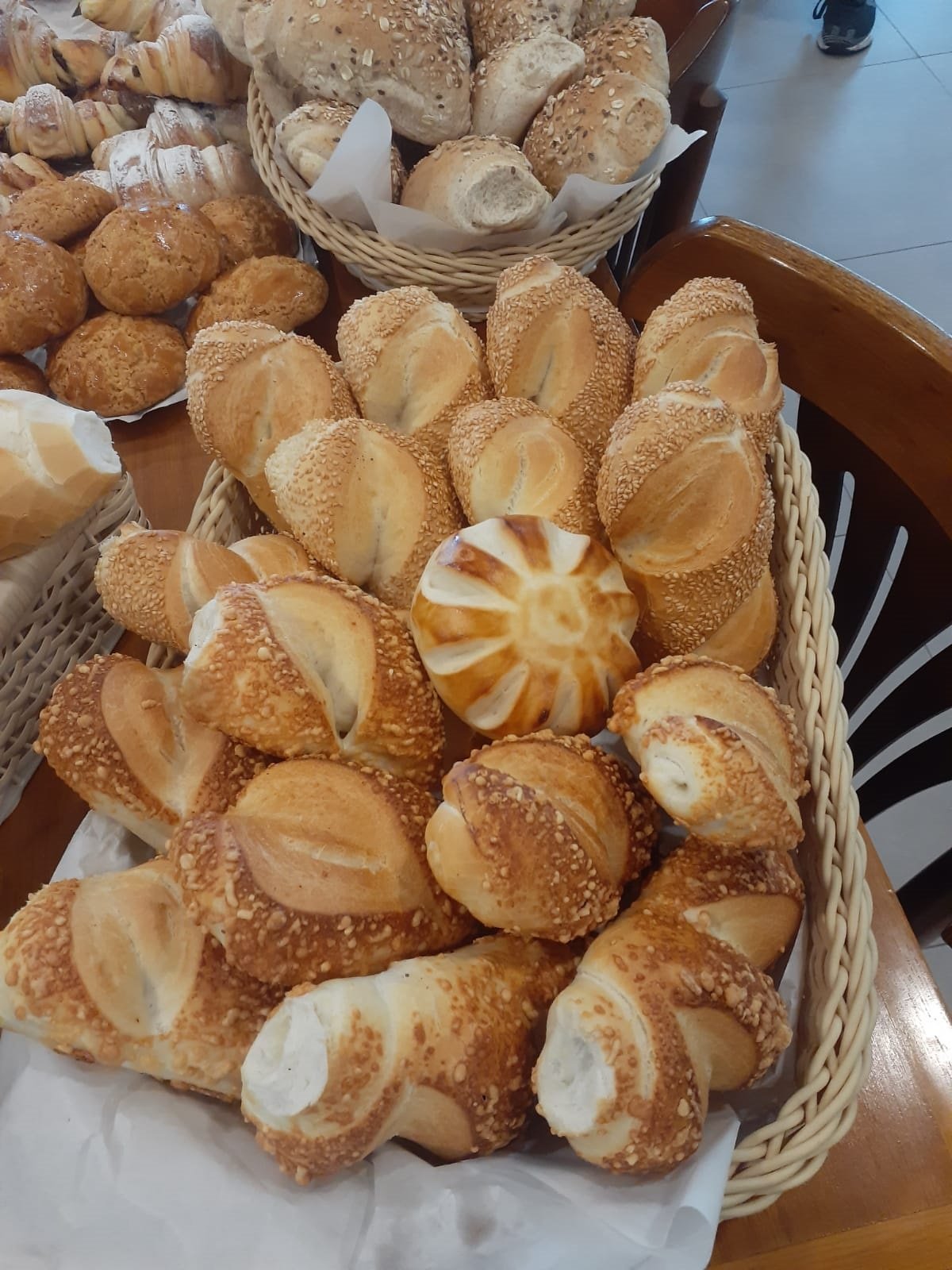 Cestos de pães variados com gergelim e pão doce em padaria.