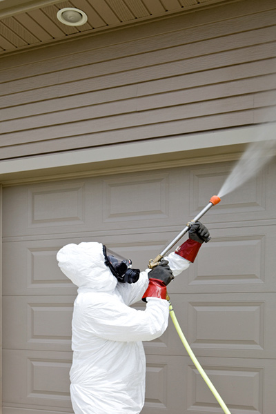 Pest control worker spraying insecticide on garage Pest control worker spraying insecticide on garage