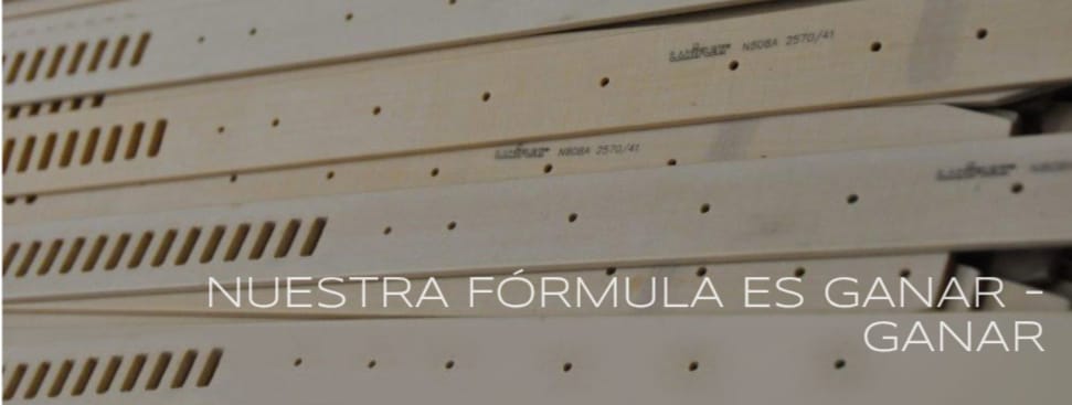 Planchas de madera apiladas con ranuras y el texto 'Nuestra fórmula es ganar-ganar' impreso en ellas.