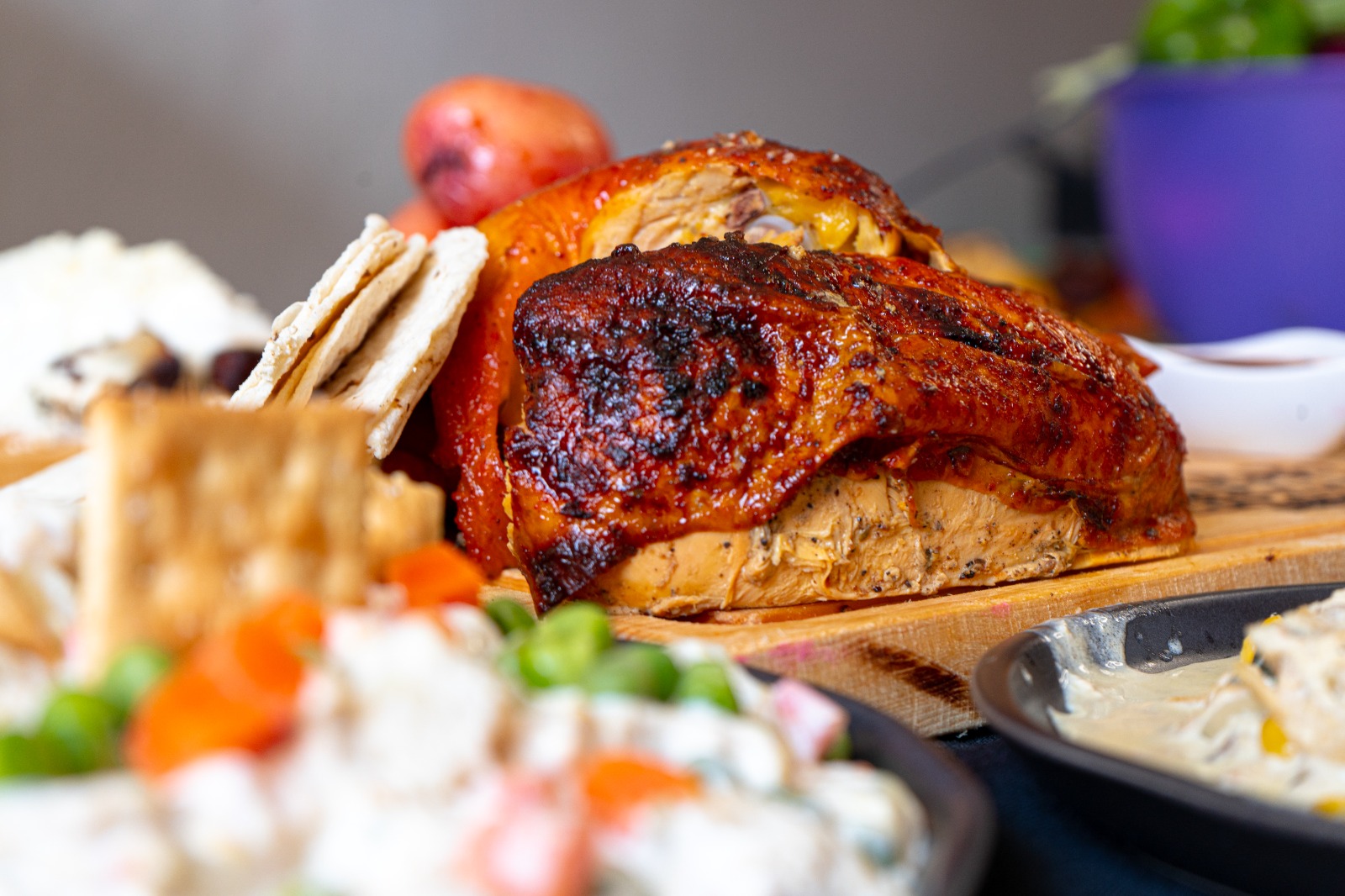 Pollo asado jugoso con piel dorada y crujiente servido en tabla de madera con ensaladas y acompañamientos