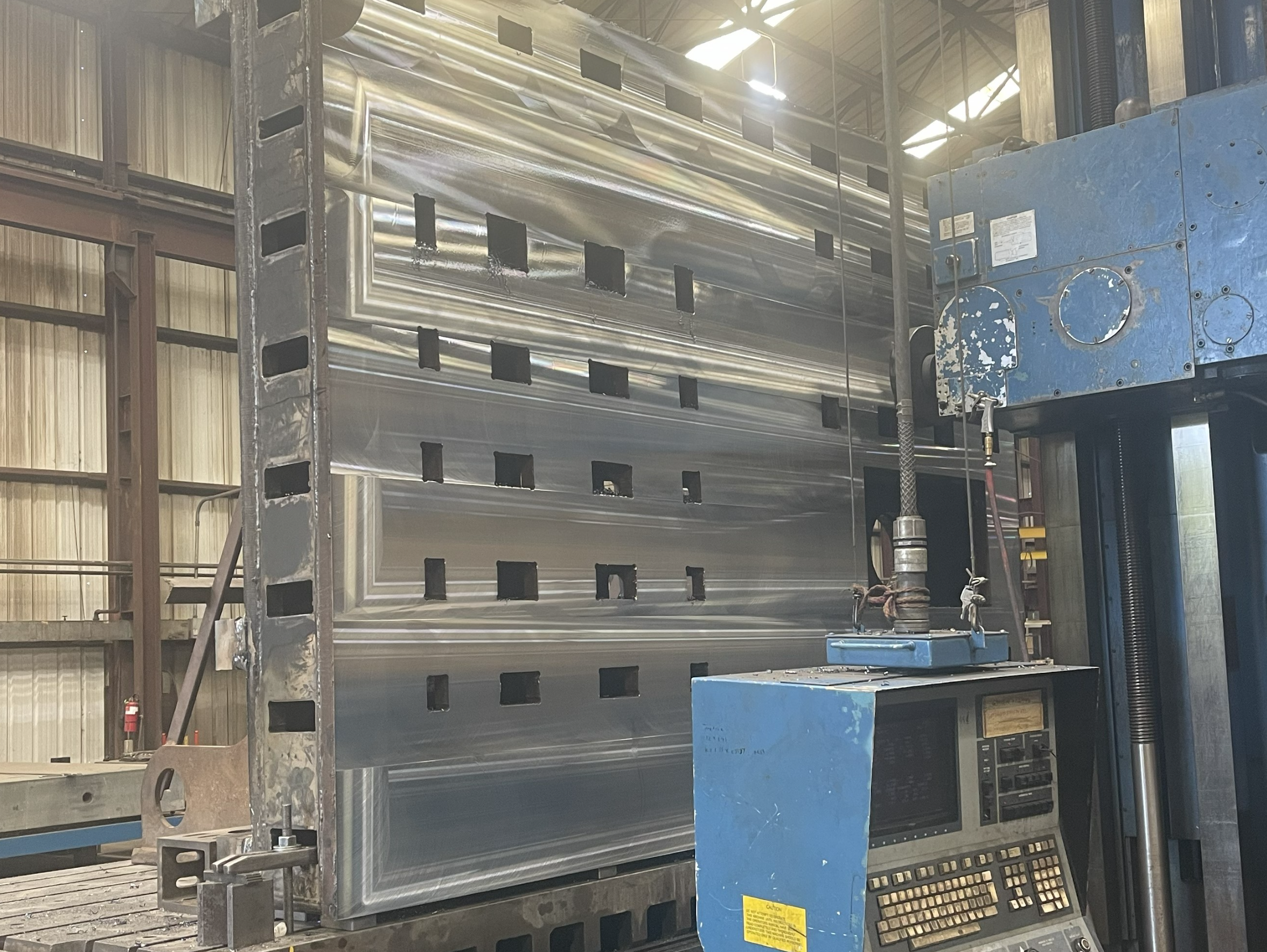 Engineer working with industrial machinery in a modern manufacturing facility, focused and wearing protective gear.