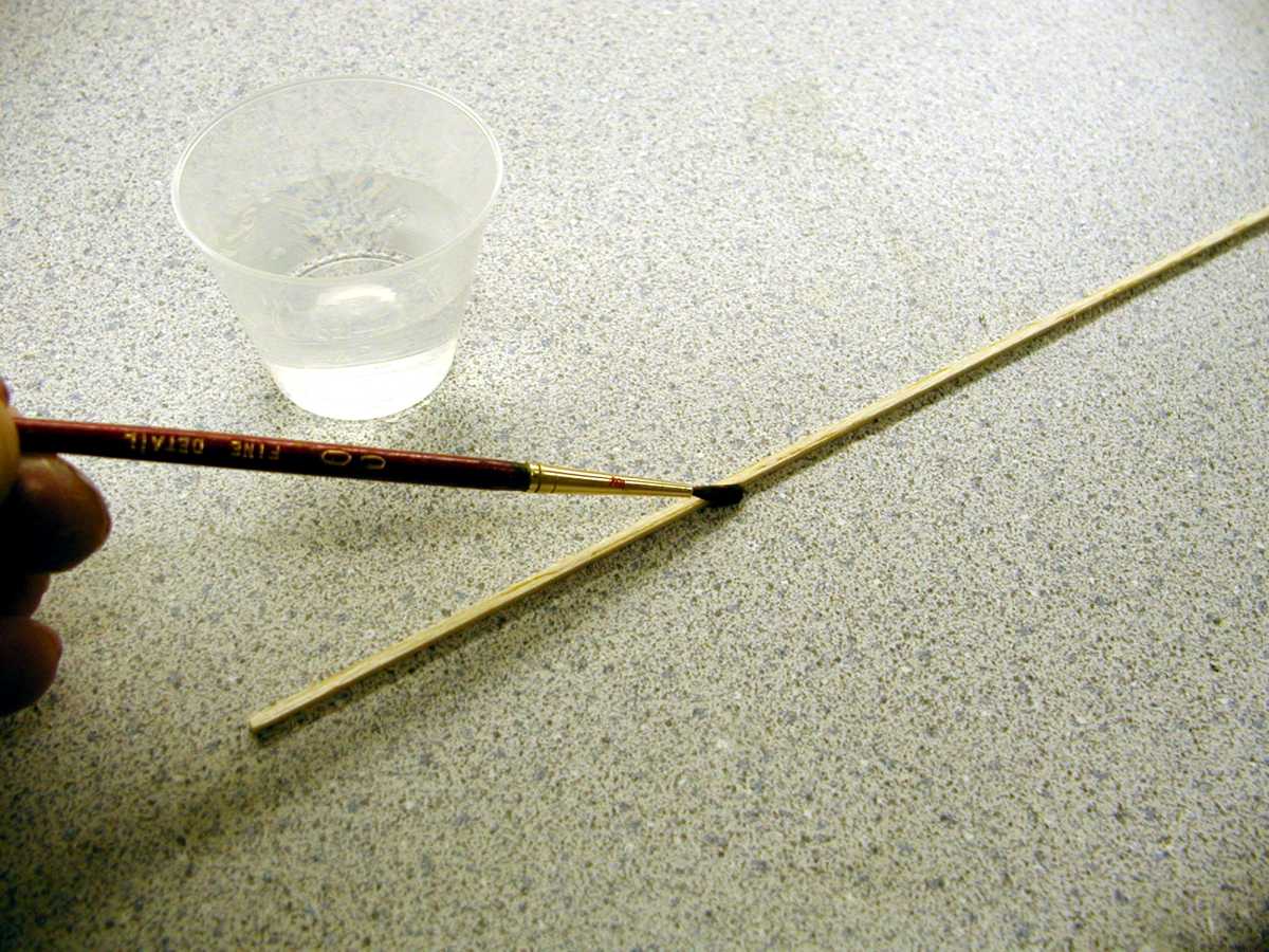 Begin by wetting the balsa strip in the area to be formed. You can do that with a paint brush and some water. We actually just place the wood in our mouth and wet it with saliva. Let the water soak in for a minute or so.