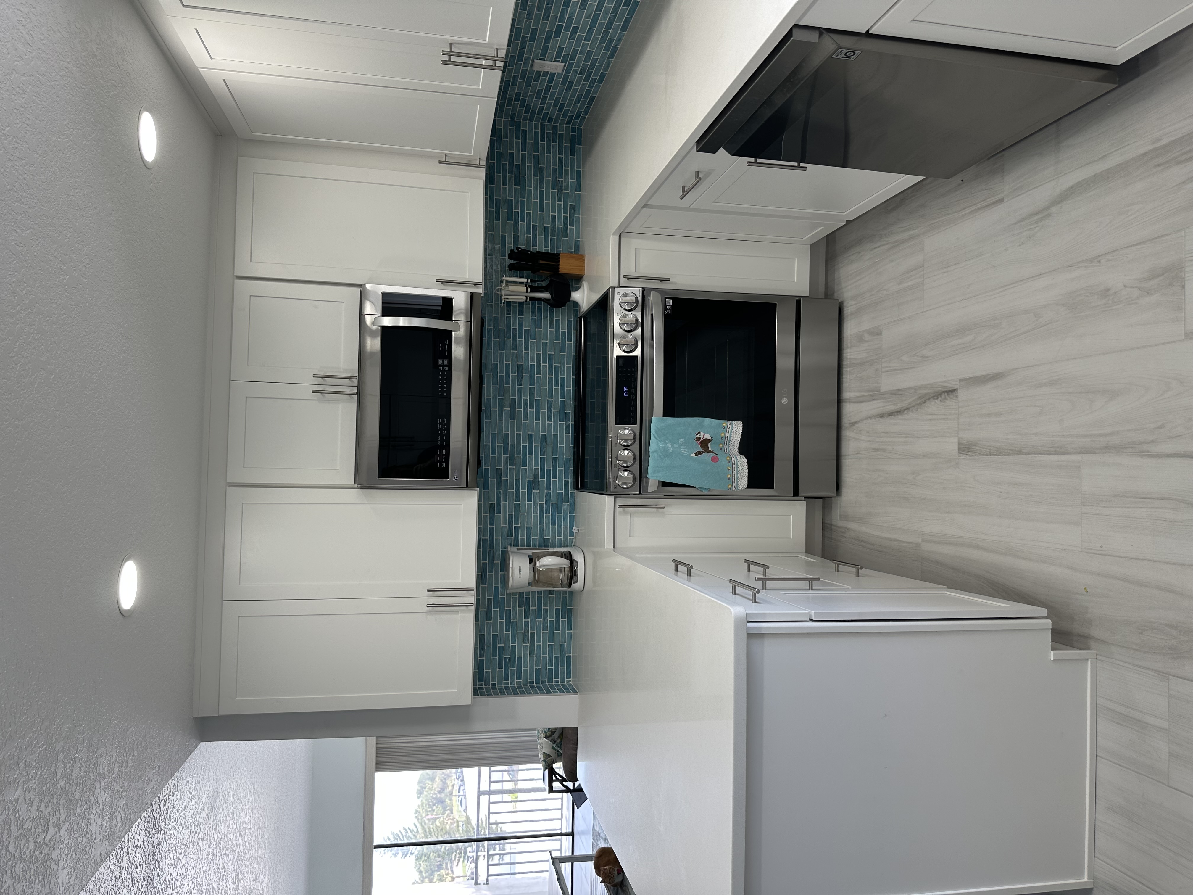 Stunning kitchen showcasing Woodland White large plank floor tiles installed throughout condo.