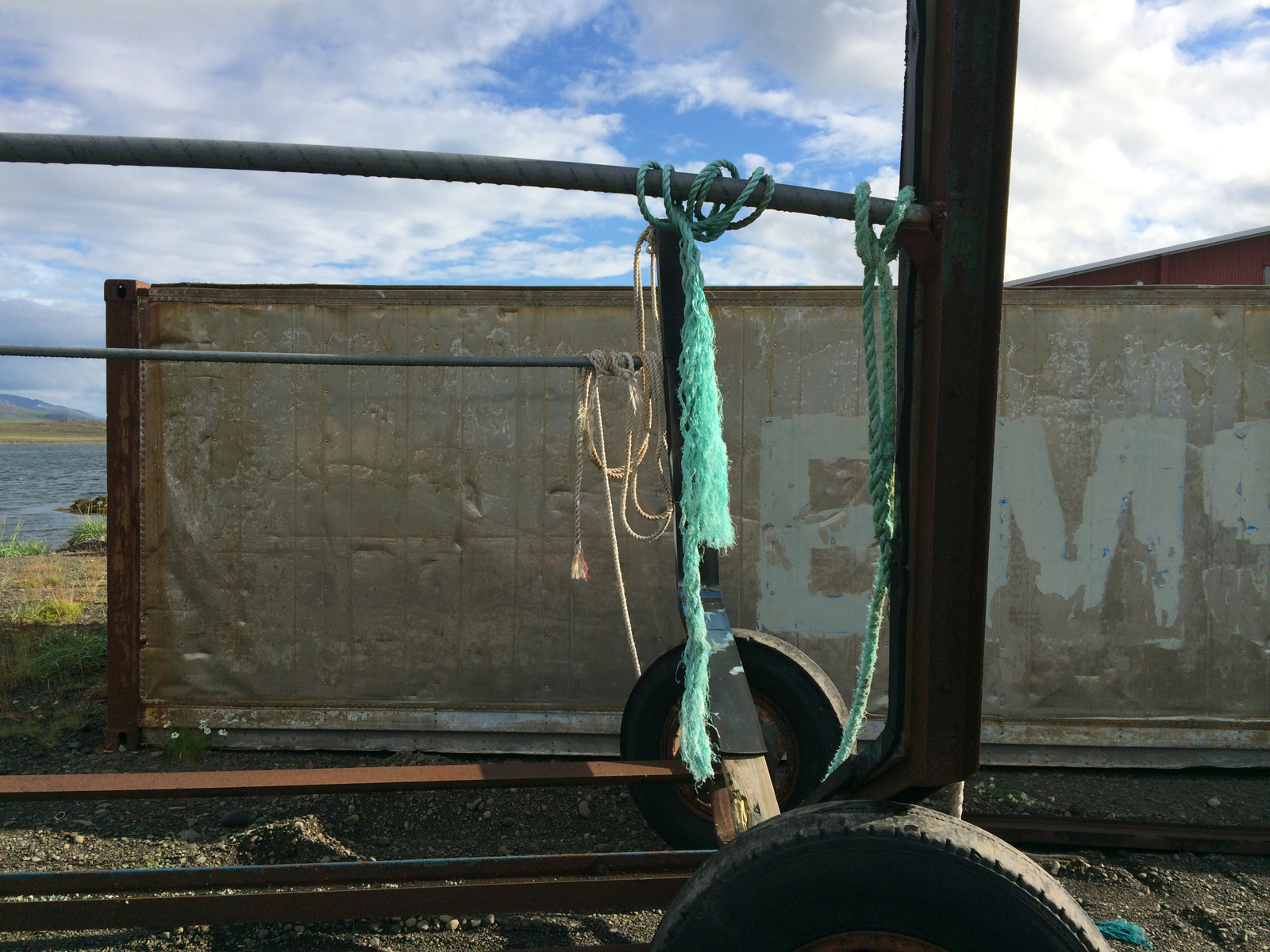 Frayed teal-colored and white rope hangs from an old rusty metal trailer frame.