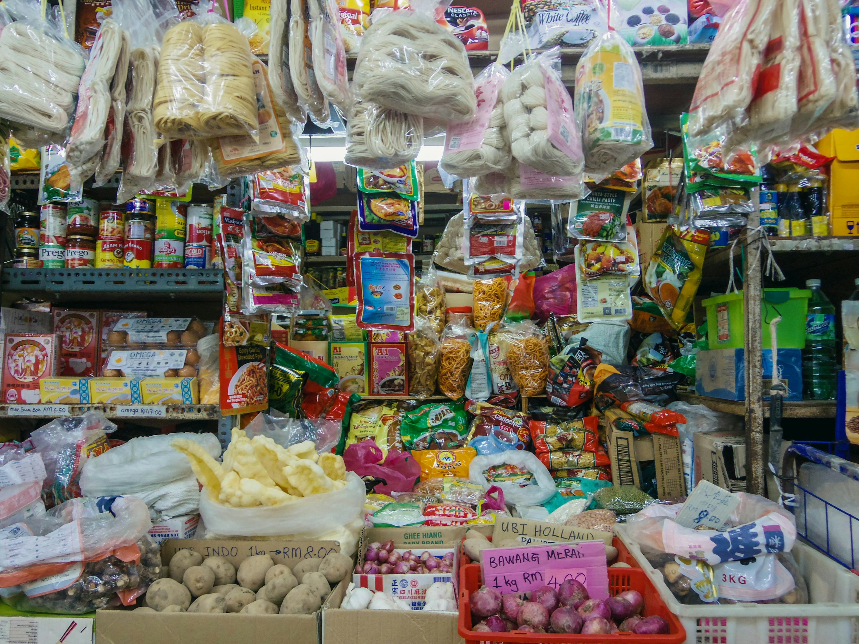 Interior de un supermercado moderno con estantes llenos de productos alimenticios y bebidas, iluminación clara y grandes ventanas al fondo.
