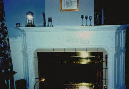 Wrap around fireplace features 22,5 degree
 angle raised paneled sides with fluted pilasters.
 The front features center carved appliques. A four
 layer mantle with dentil molding finishes fireplace,  