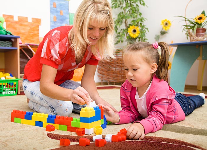 Teacher and child are playing with bricks Teacher and child are playing with bricks