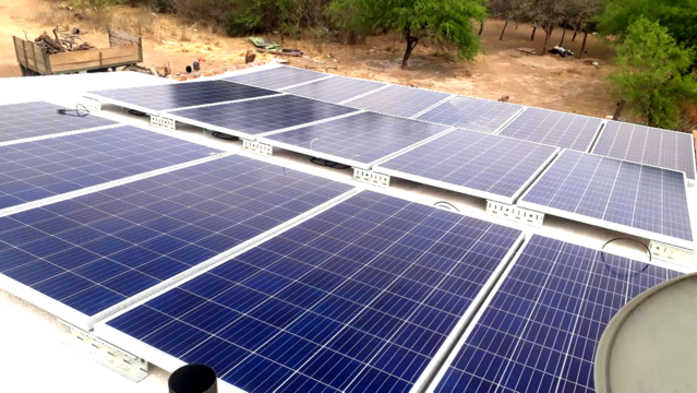 Paneles solares instalados en un techo con fondo de vegetación y campo abierto.