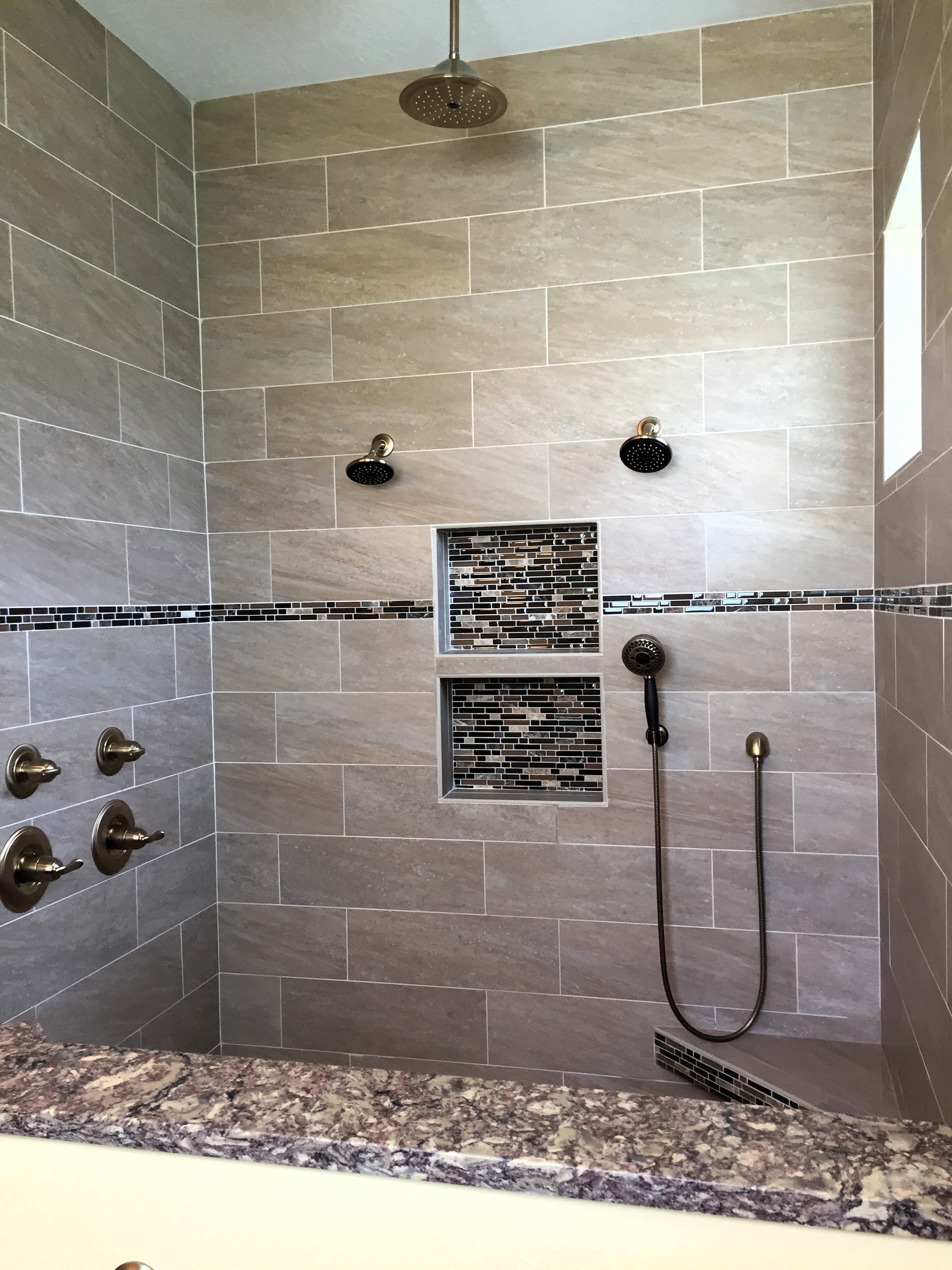 Large updated shower featuring polished porcelain tiles with mosaic accent band and double niches.