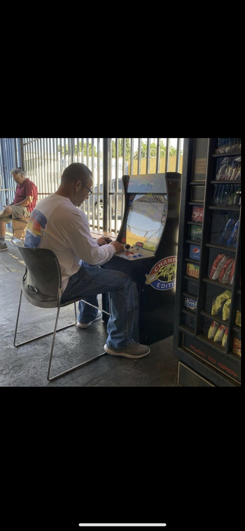 Man playing retro arcade game beside snack vending machine in an indoor arcade
