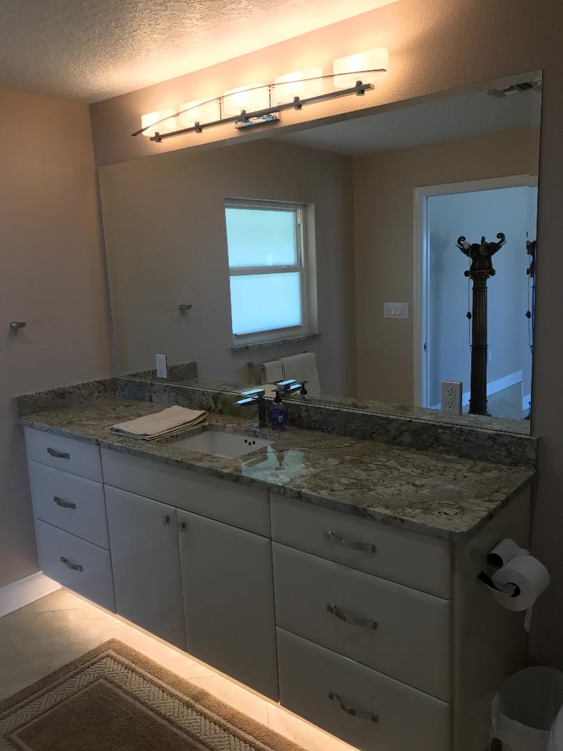Featuring a sleek white vanity with under cabinet lighting.