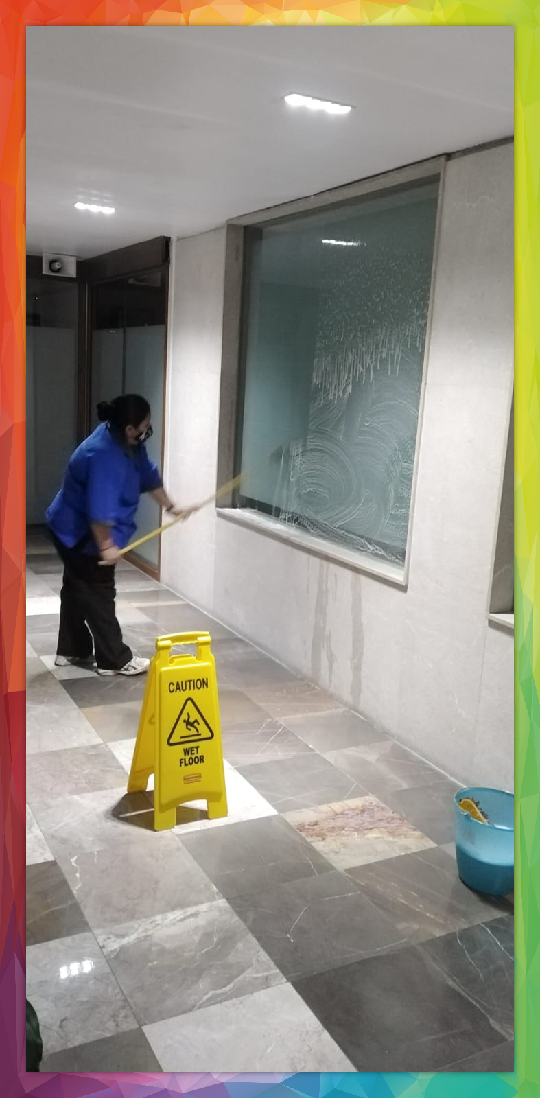 Persona con uniforme azul limpiando un ascensor con guantes rojos.