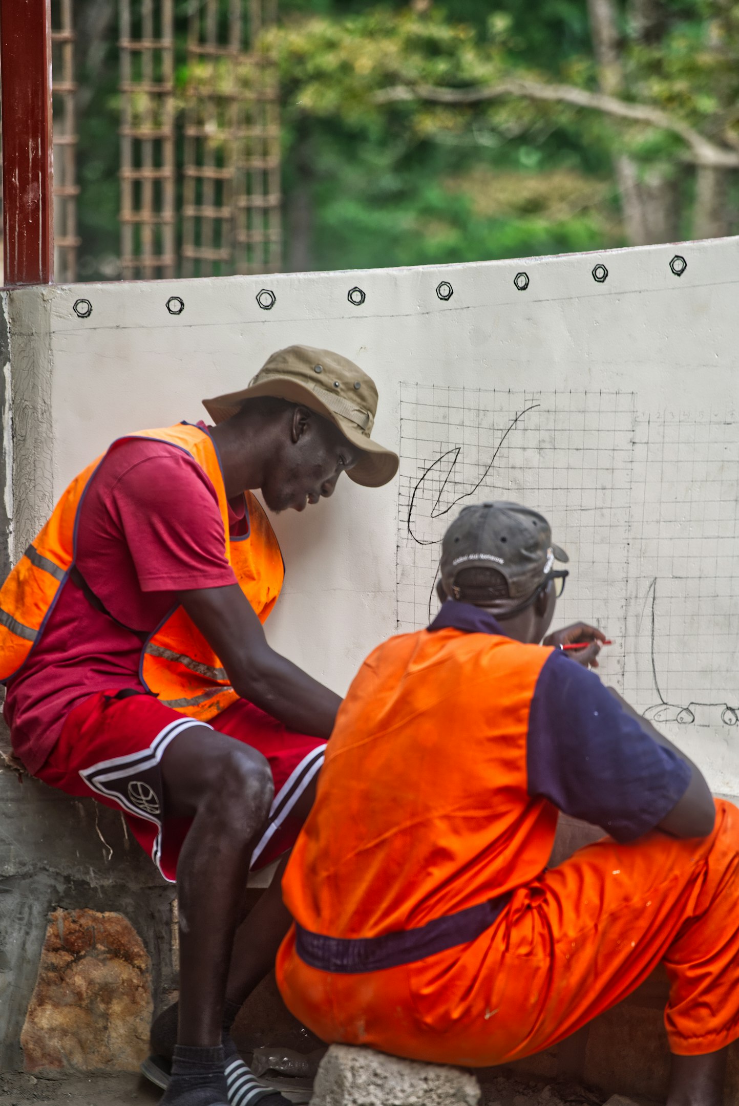 Two men in orange vests reviewing plans