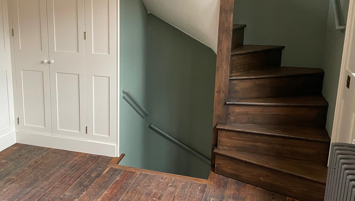 man in black t-shirt and gray pants standing near white wall