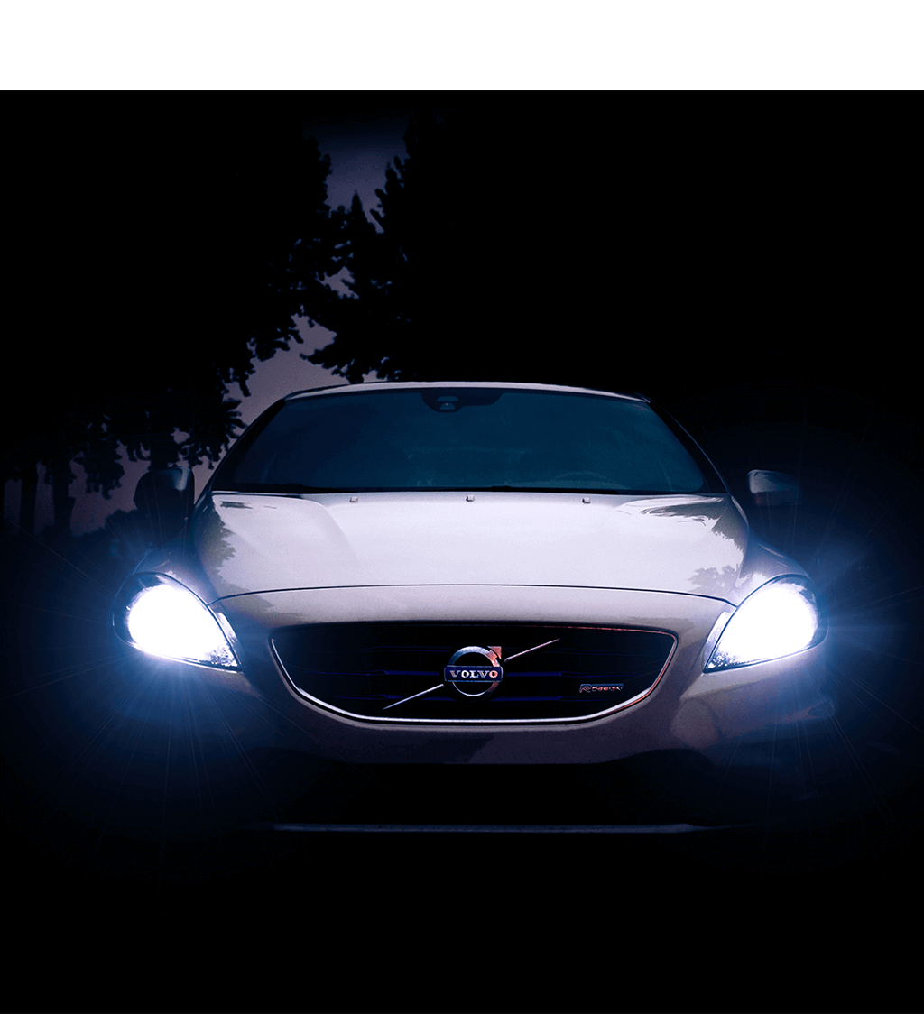 a gray volvo with its headlights on in murky lighting
