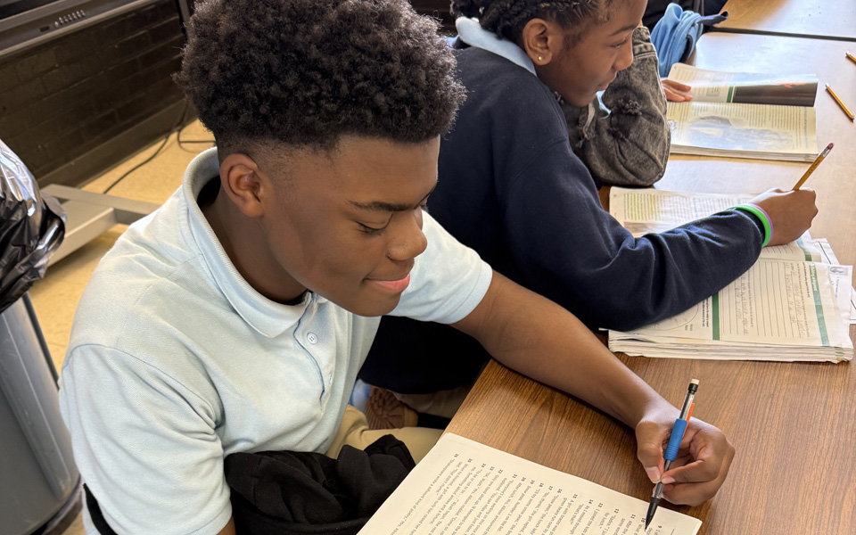 Student reading and writing at a desk