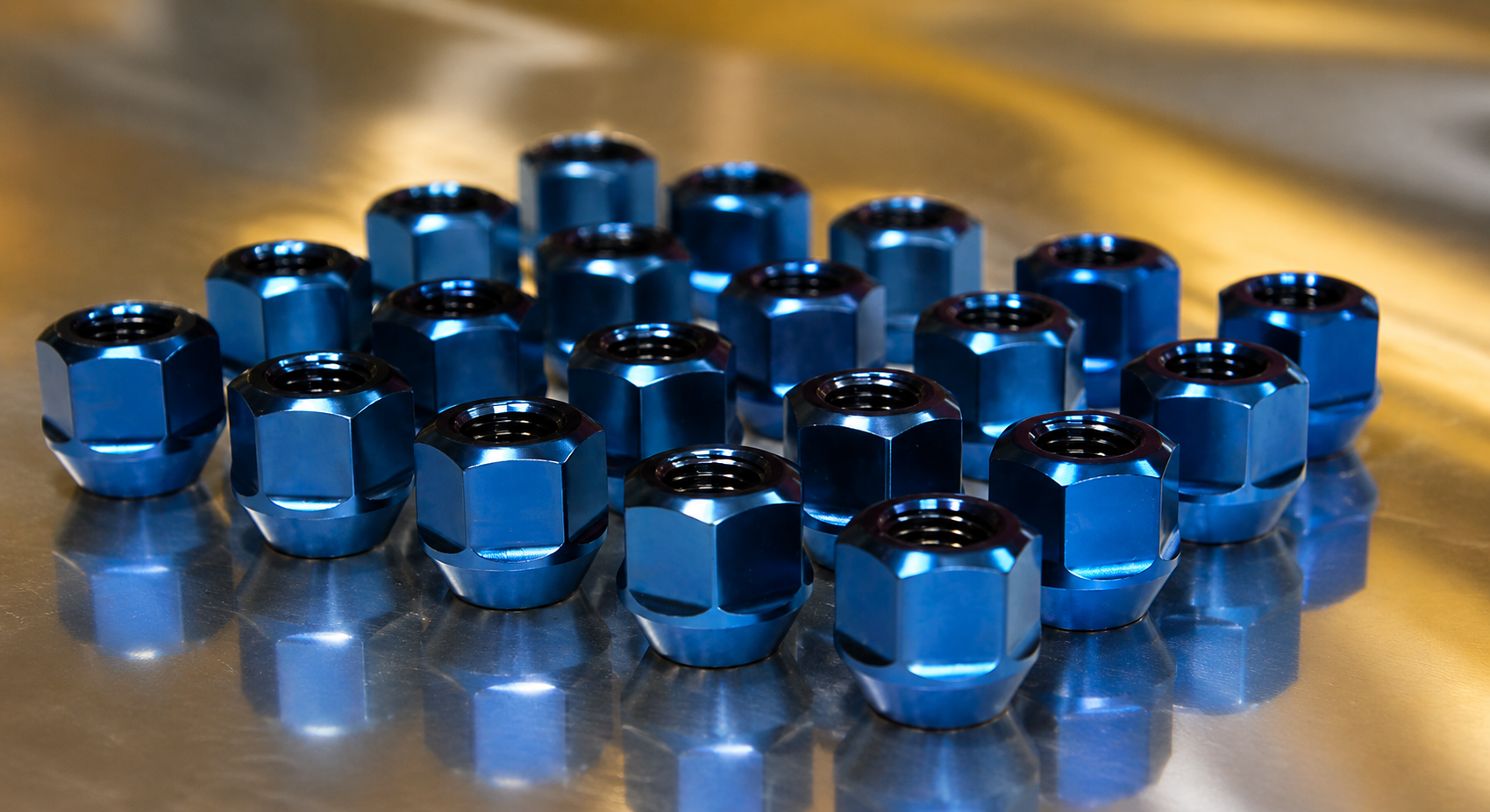Colorful aftermarket lug nuts and wheel bolts displayed in front of a sports car alloy wheel
