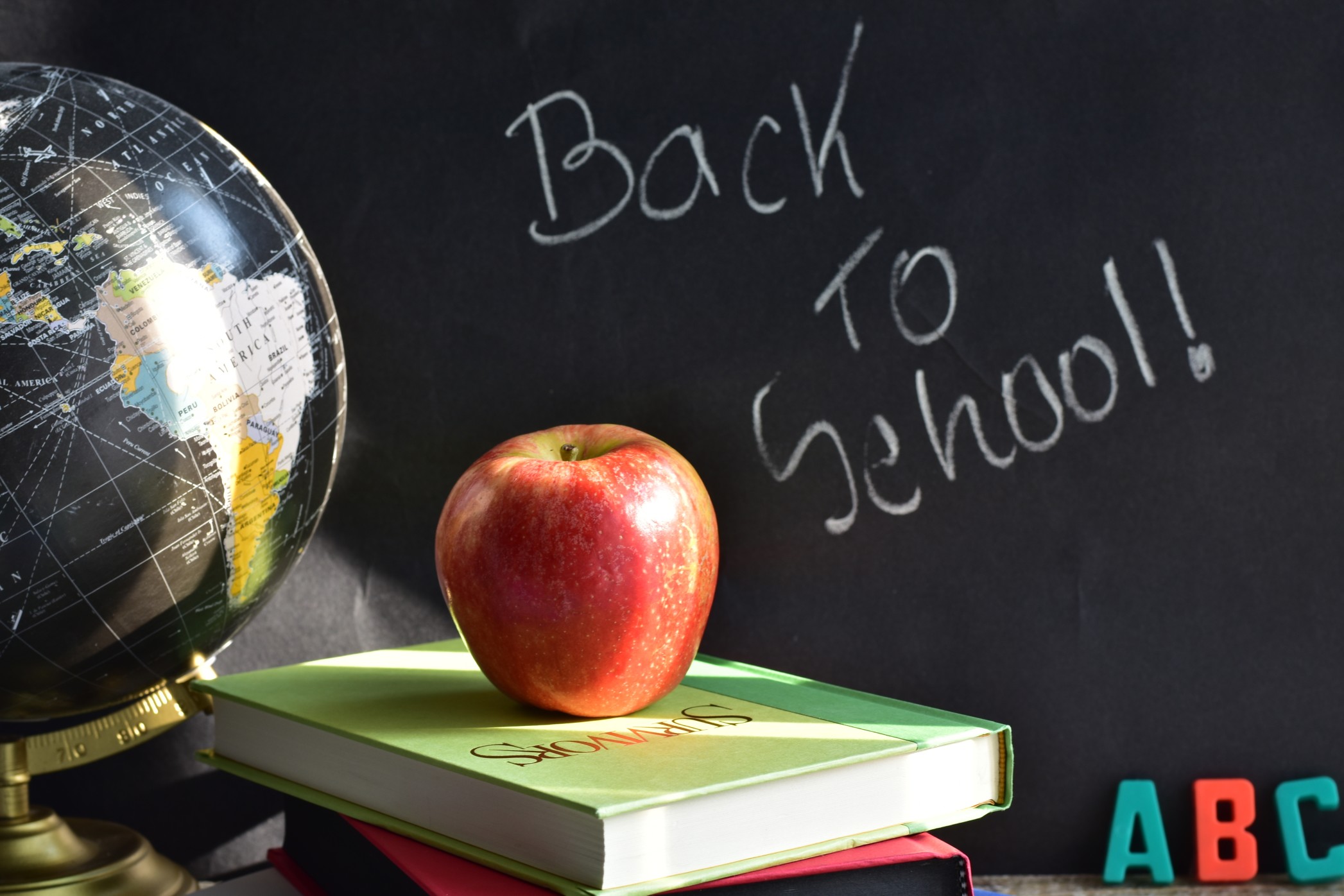 Blackboard, apple, books and globe in a classroom
