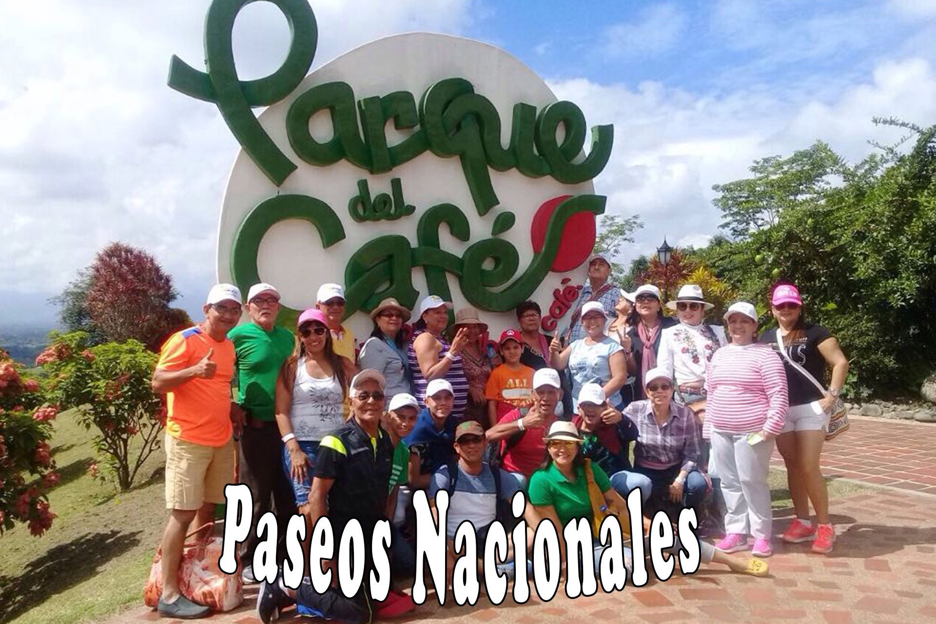 Grupo de personas posando frente al cartel del Parque del Café rodeado de vegetación.