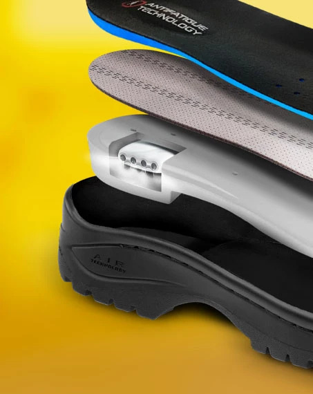 Botas de cuero negro y amarillo con cordones en un entorno industrial.