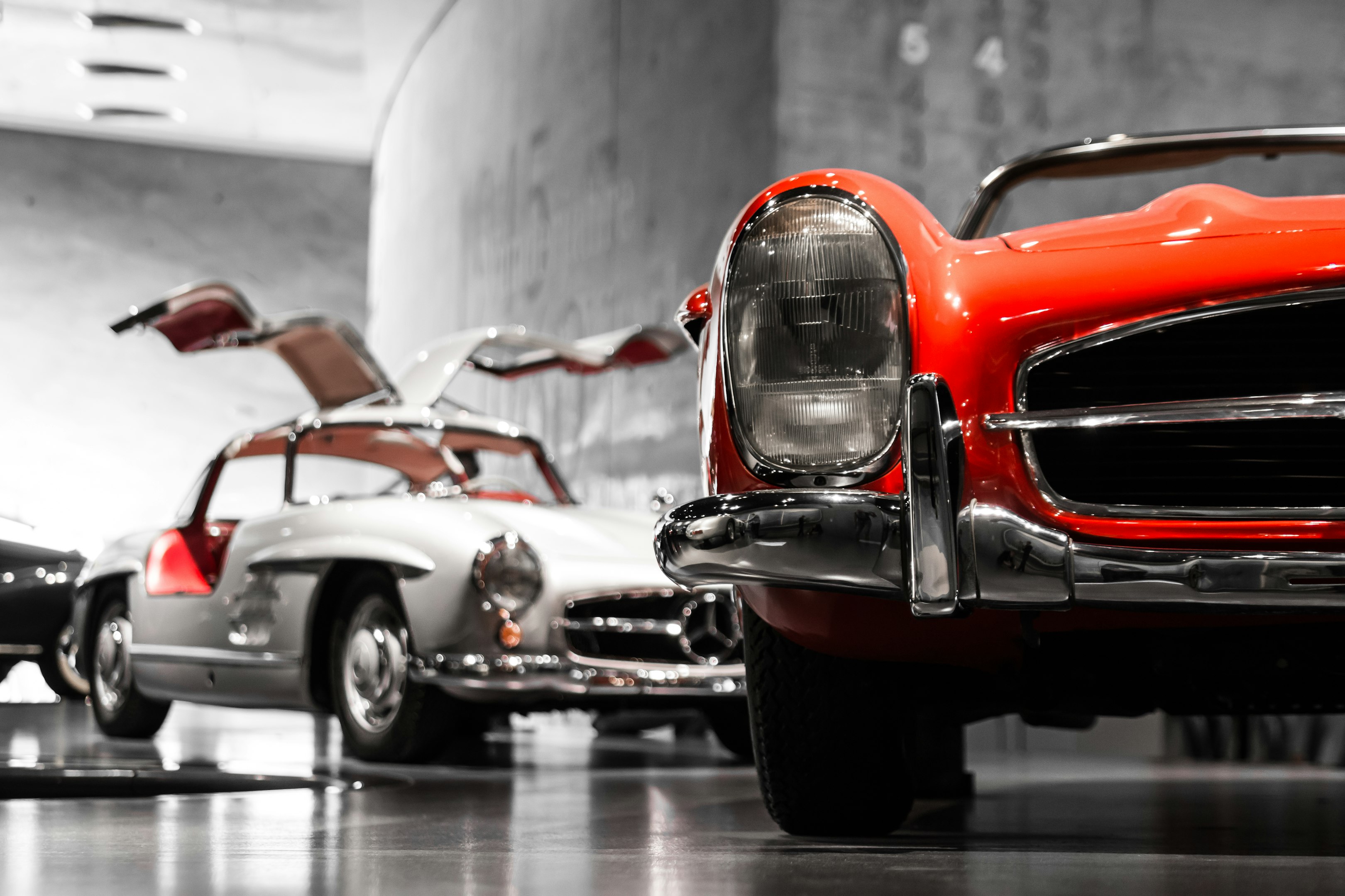 dos coches antiguos junto a una pared de hormigón gris