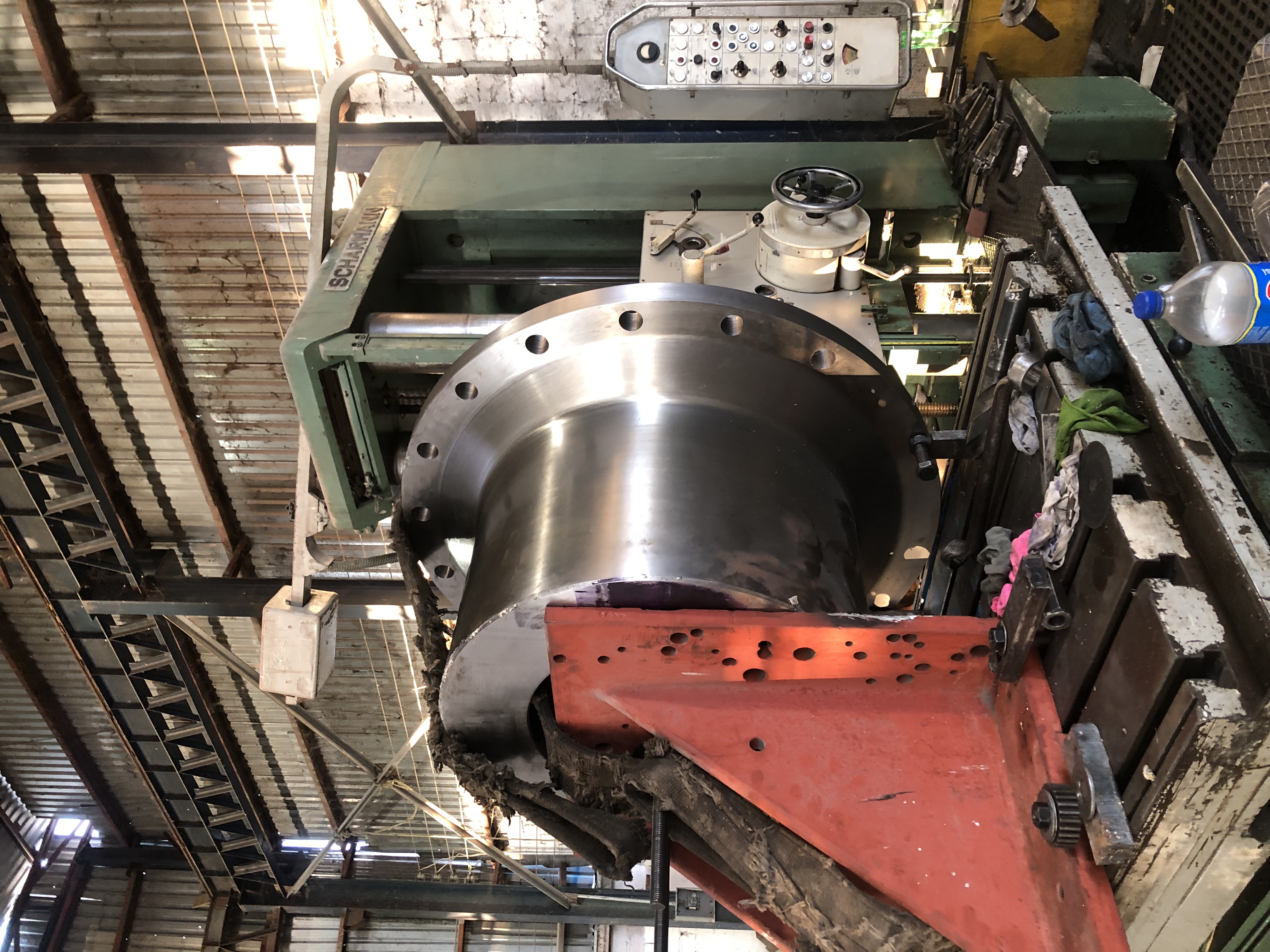 Componentes industriales cilíndricos metálicos sobre una mesa de trabajo en un taller.