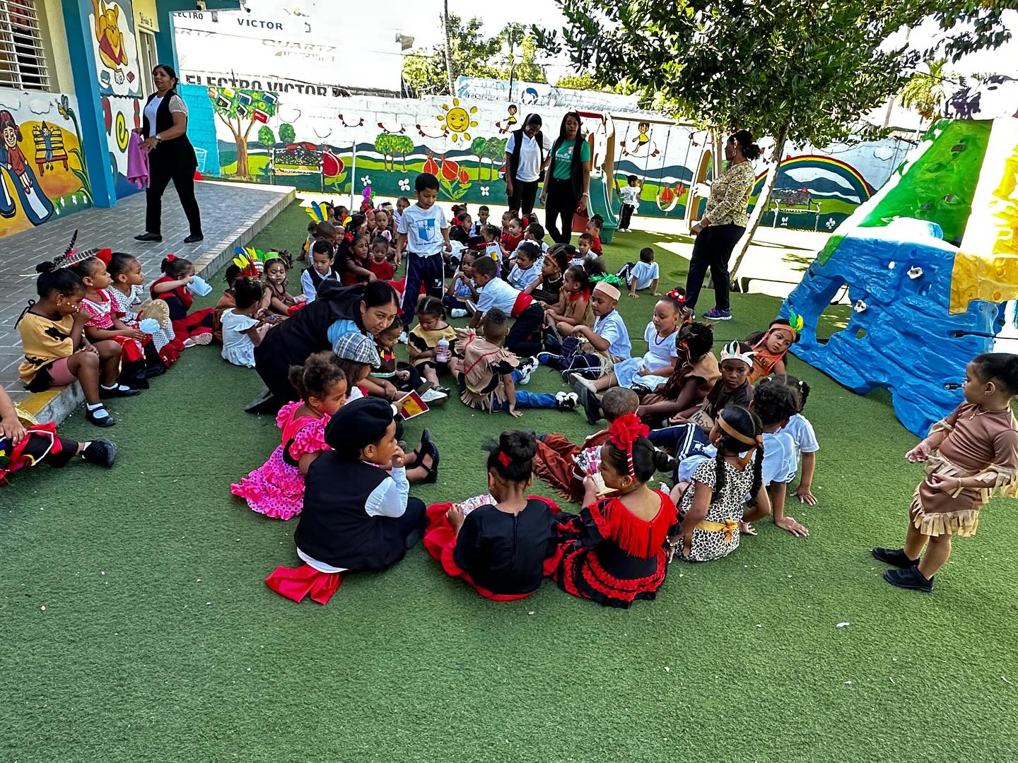Niños en un aula de clase, sentados en grupos y trabajando en actividades escolares, con mochilas colgadas en las sillas y carteles educativos en la pared. Niños en un aula de clase, sentados en grupos y trabajando en actividades escolares, con mochilas colgadas en las sillas y carteles educativos en la pared.