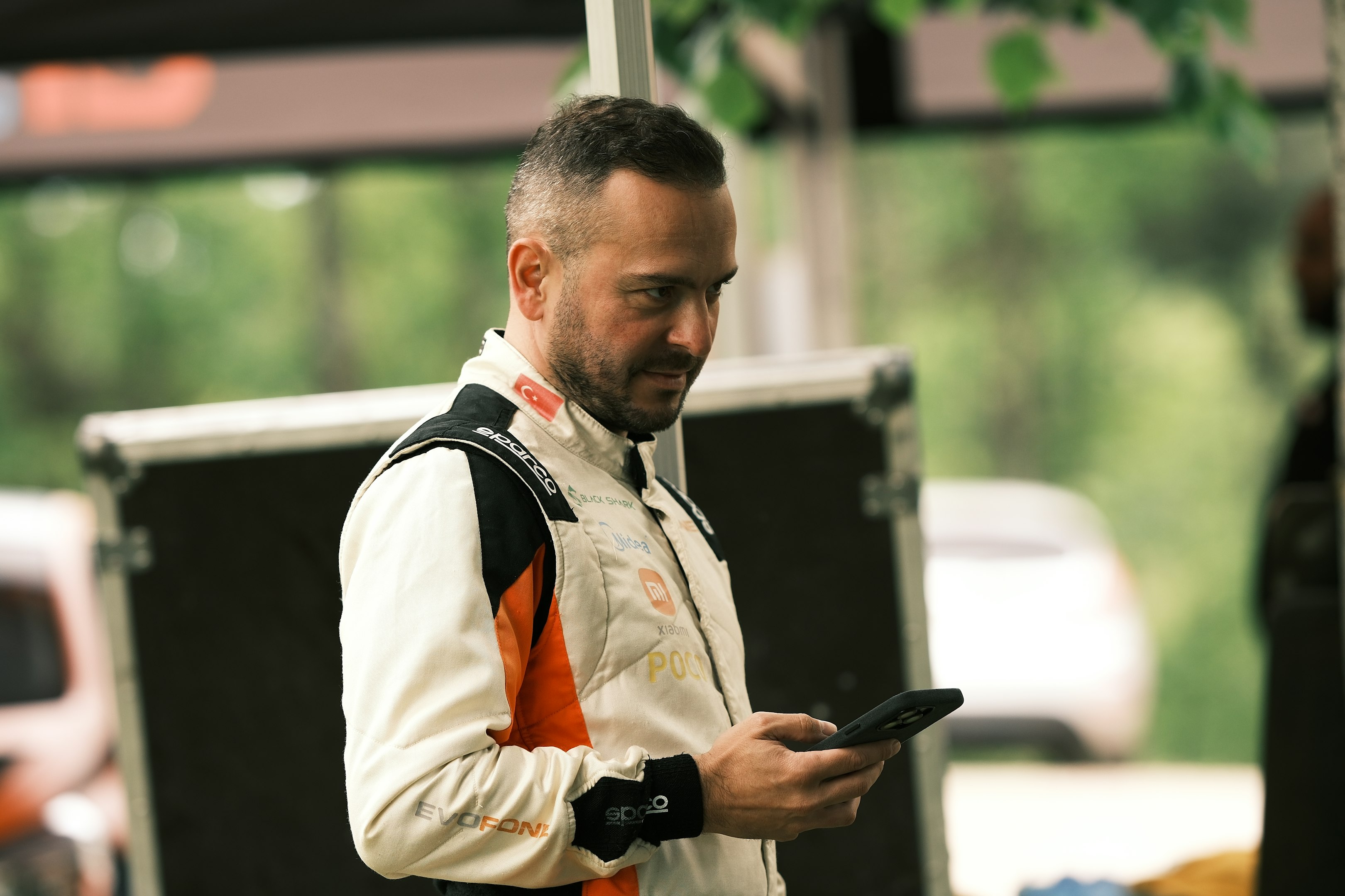 a man in an orange and white jacket looking at a cell phone