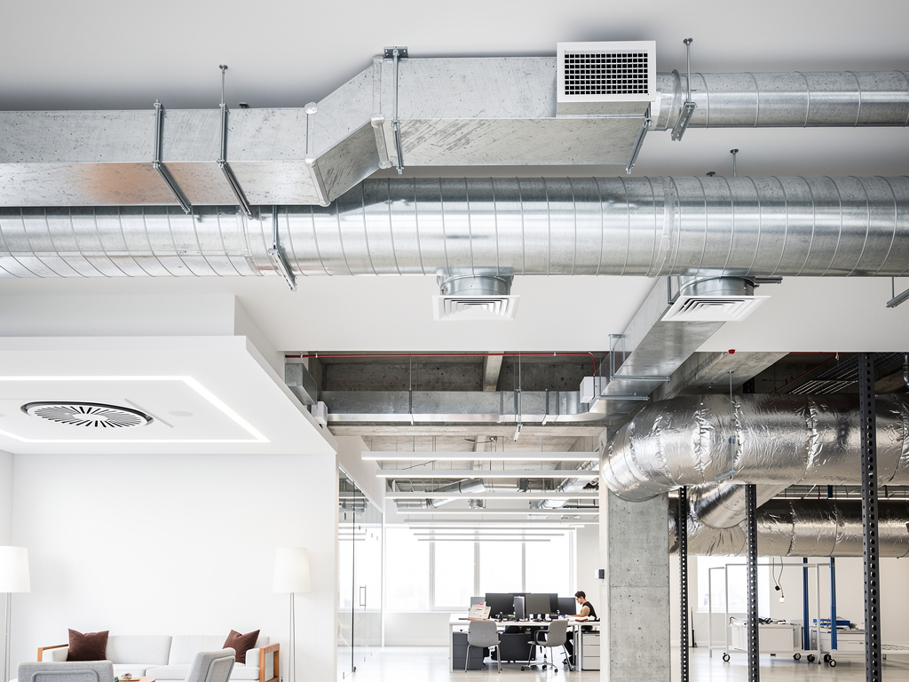 Conductos de ventilación industrial expuestos en techo de oficina moderna con sistema HVAC