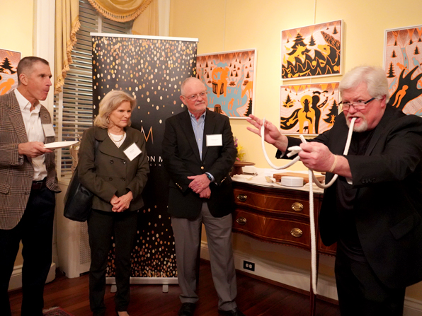 Man in a black tuxedo with bow tie sitting at a table with a glass of red wine, floral wallpaper background. Man in a black tuxedo with bow tie sitting at a table with a glass of red wine, floral wallpaper background.
