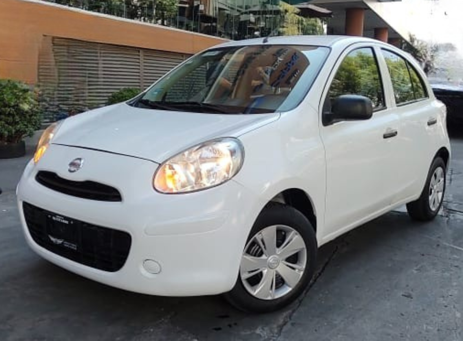 Man standing beside a white Toyota car in an underground parking lot.