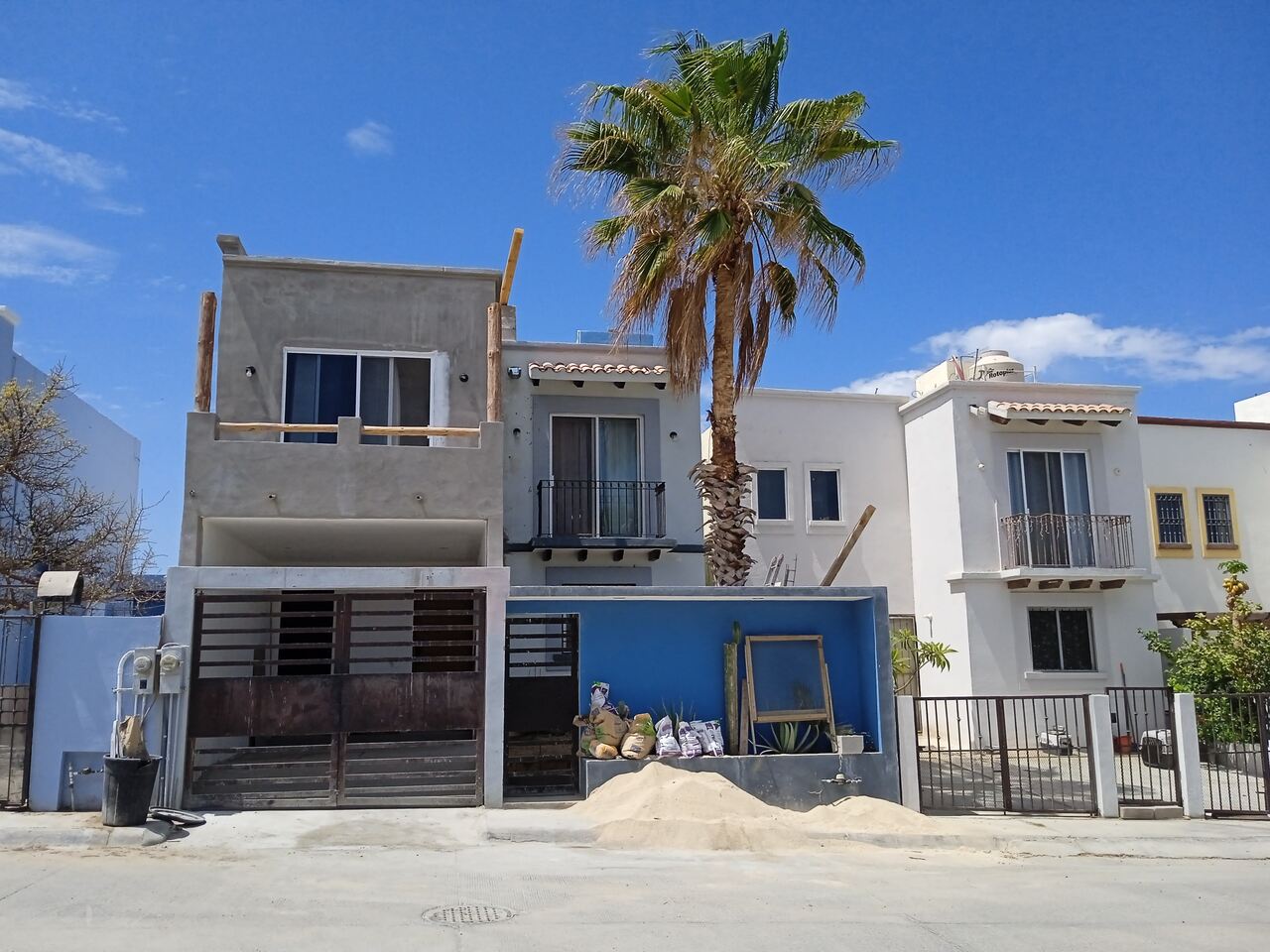 Edificio en construcción con estructura de acero y muros de piedra bajo un cielo azul.