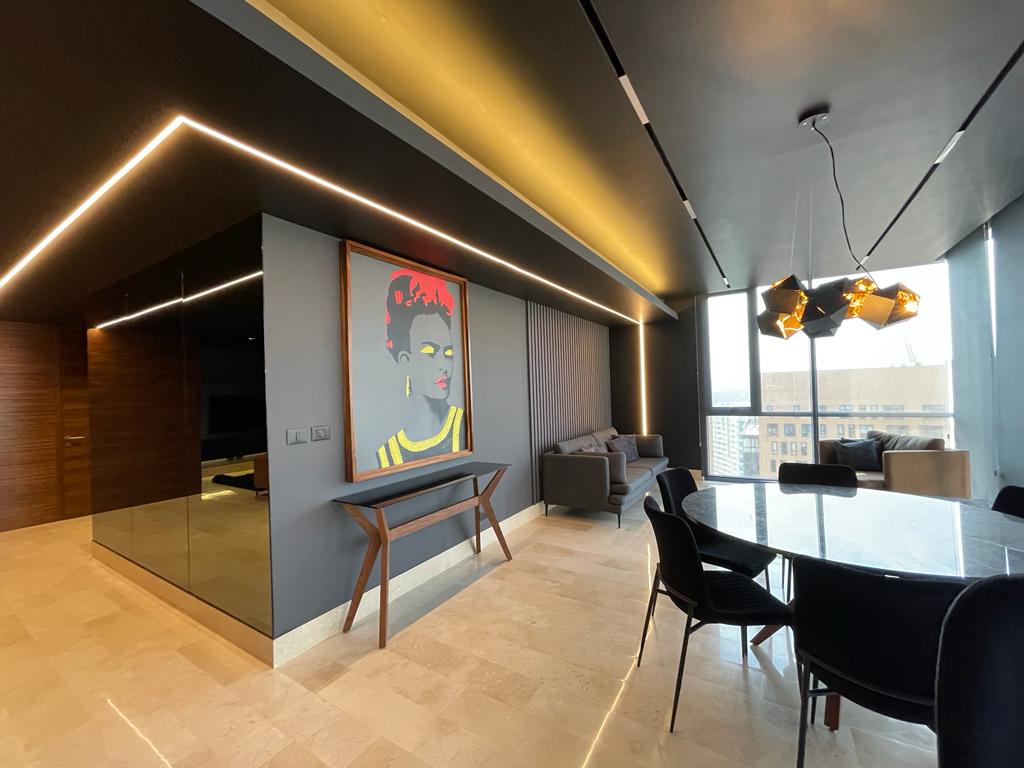 Sala moderna con mesa de comedor, iluminación empotrada y arte contemporáneo en la pared.