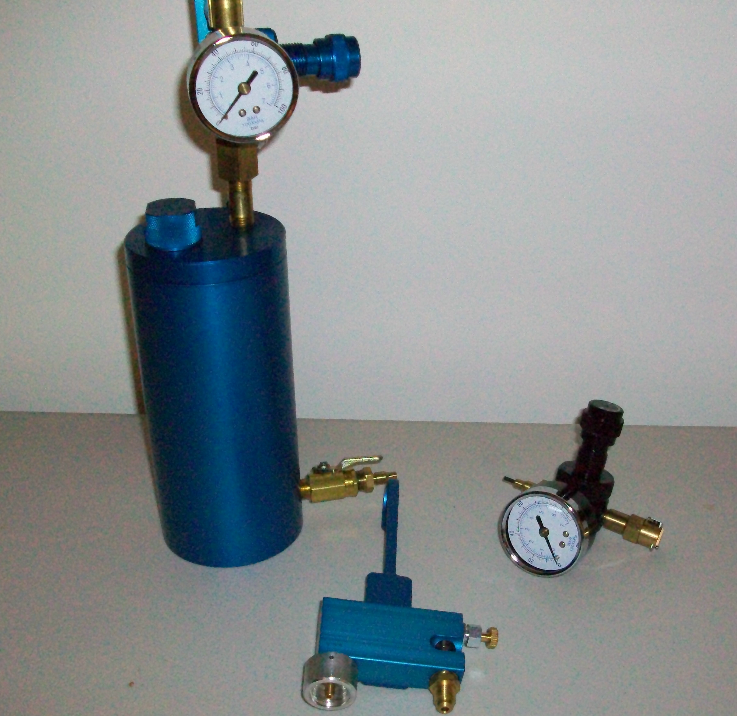 Blue pneumatic air regulator system with pressure gauges and valves on a gray surface