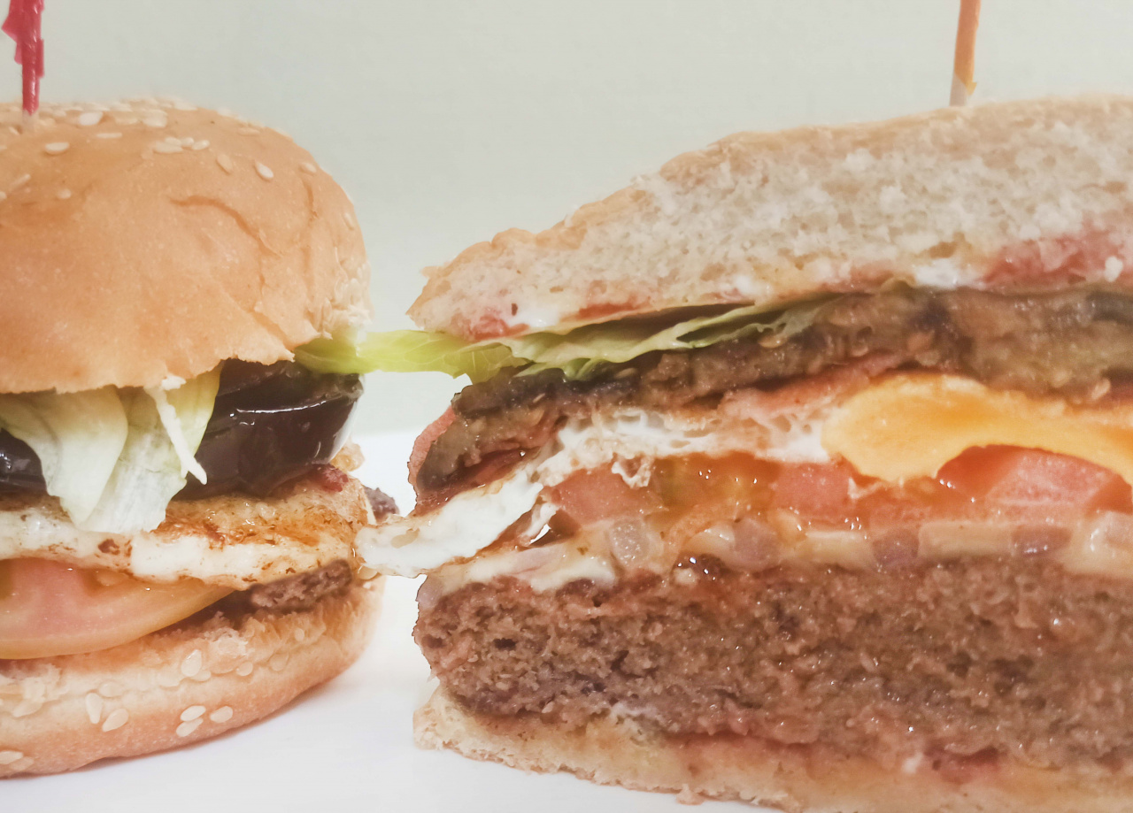 Rica Hamburguesa con Carne de Res, Bacon, American Cheese, huevo Frito, Berenjena y pimientos marinados, tomate, lechuga, cebolla, Aderezada con catchup, salsa cheedar y mayonesa.