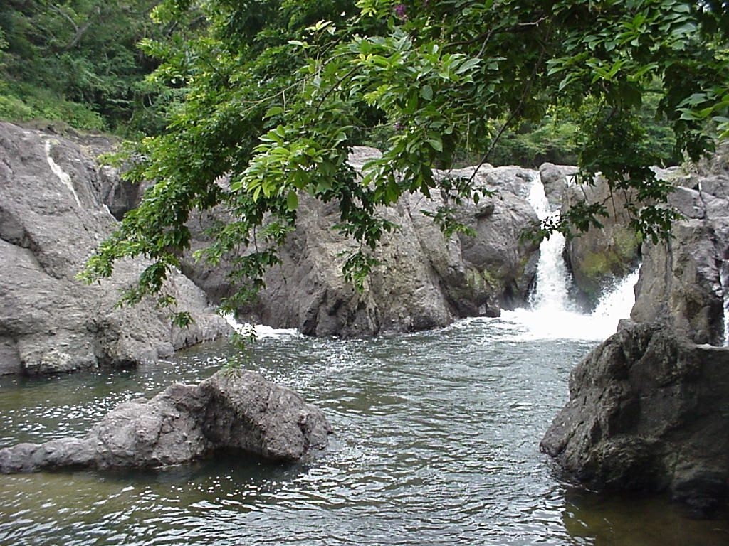 Cascada rodeada de rocas y vegetación exuberante en un entorno natural. Cascada rodeada de rocas y vegetación exuberante en un entorno natural.