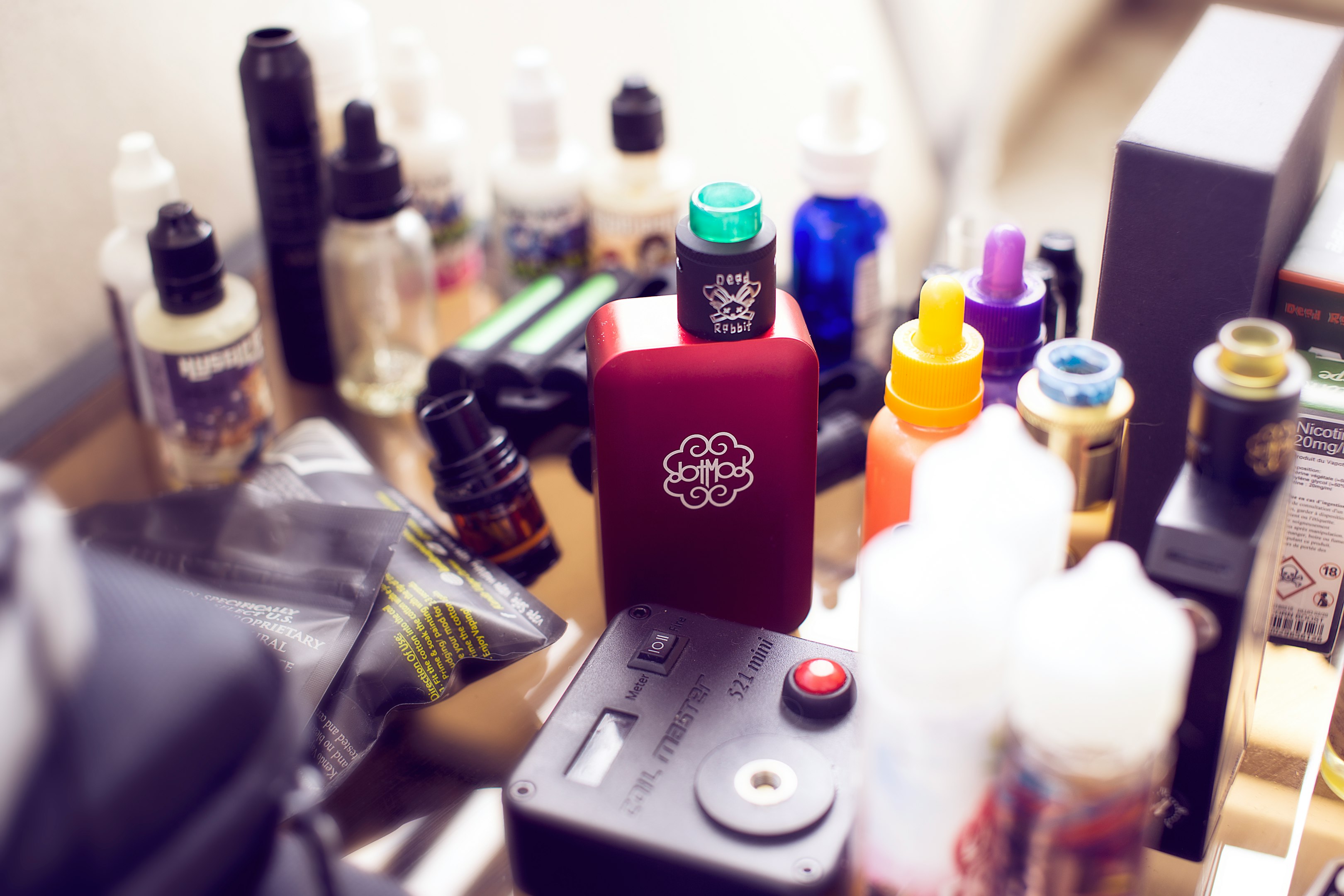mod vape de caja roja al lado de botellas de e-juice