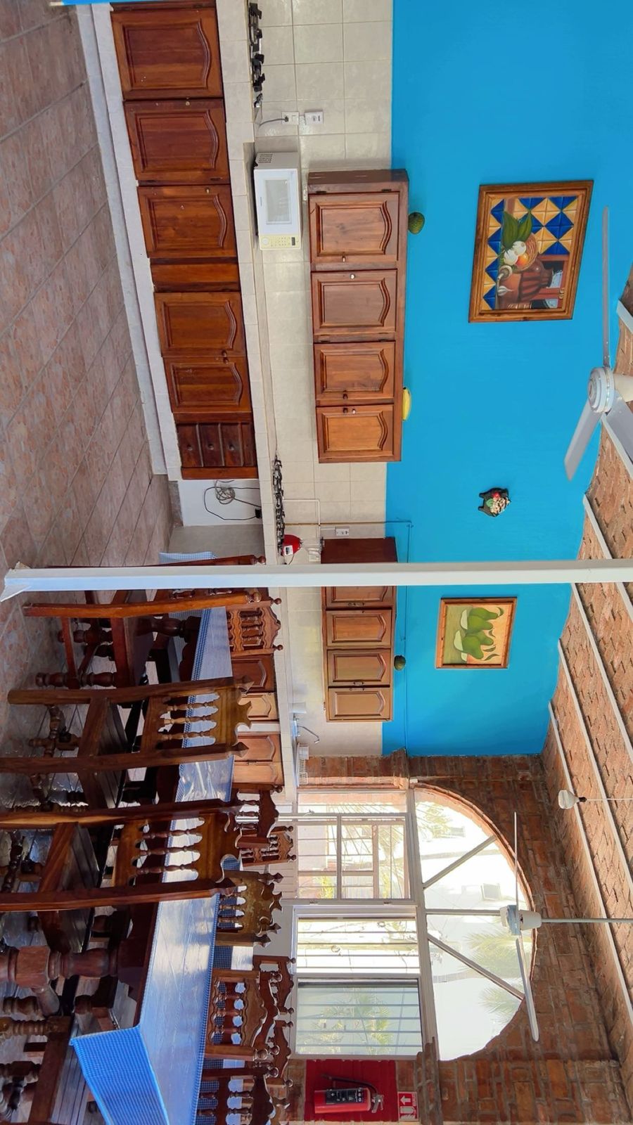 Habitación moderna y elegante con cama grande, escritorio con silla, televisor grande montado en la pared, ventanas amplias y detalles de madera.