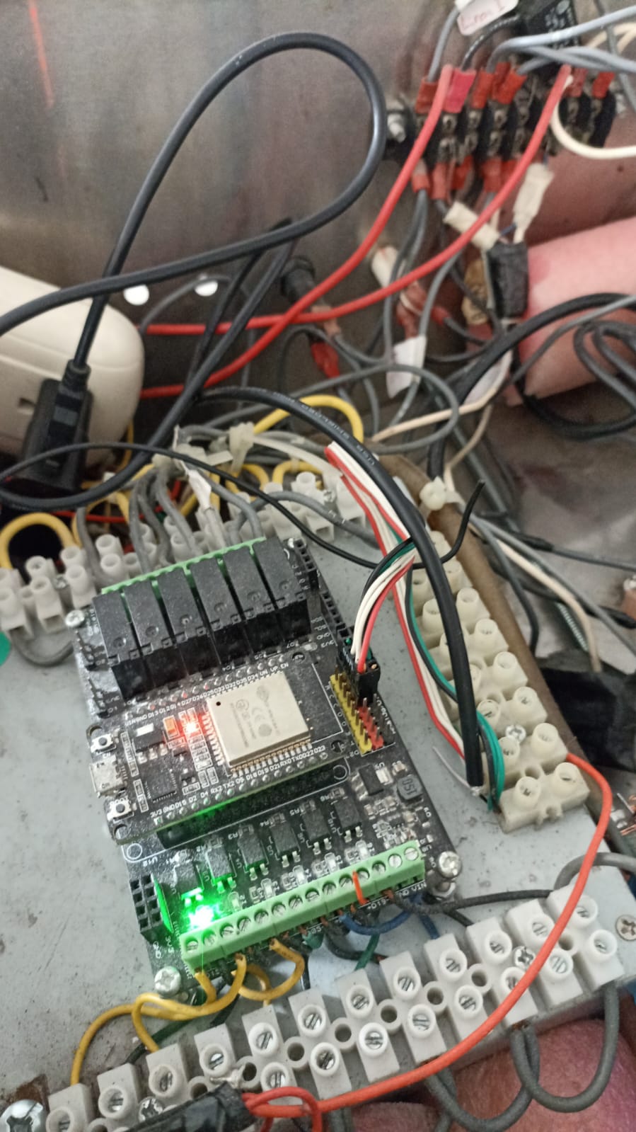 Hombre con gafas trabajando en un escritorio con múltiples dispositivos electrónicos en una oficina moderna.