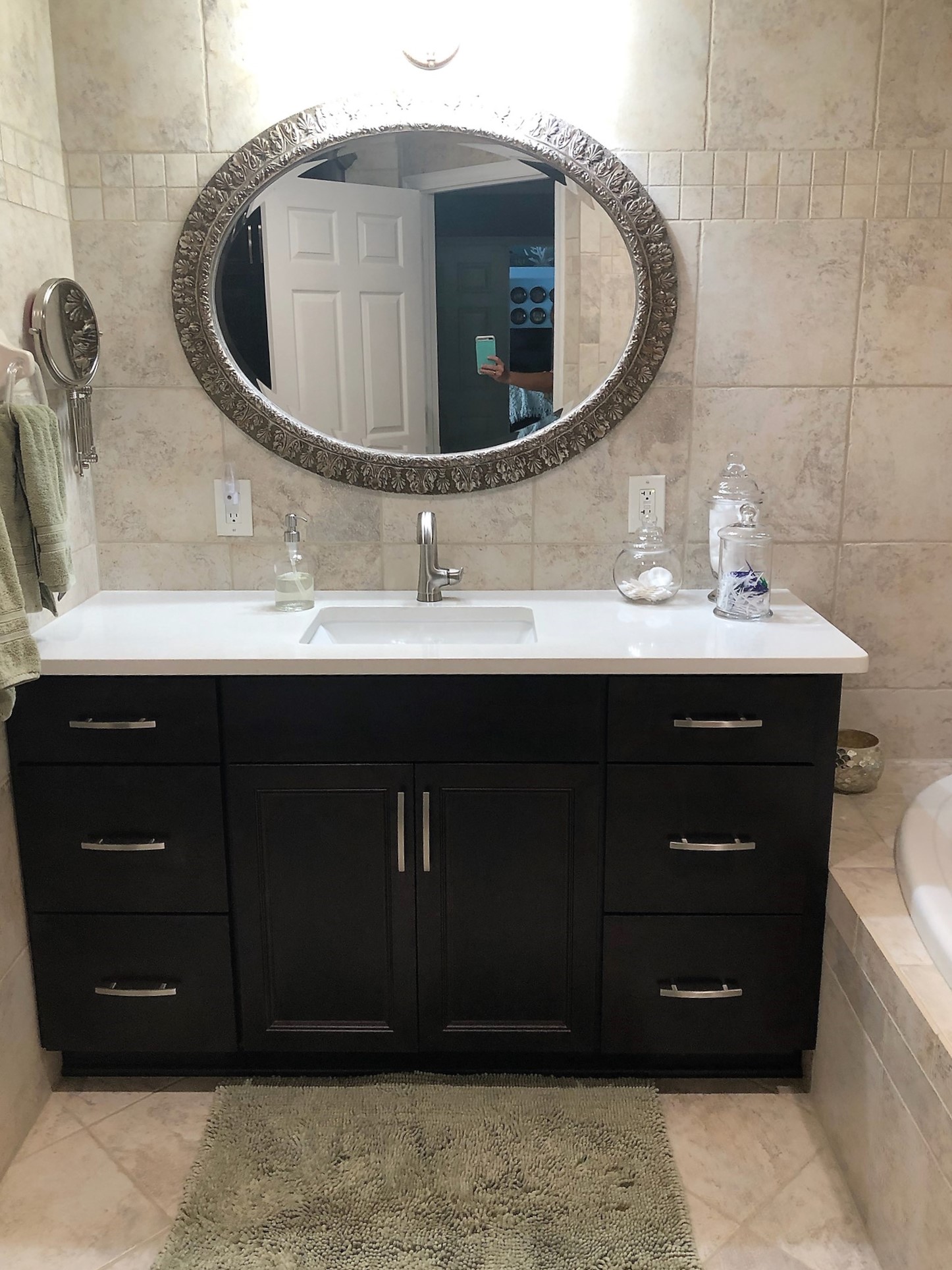 Single painted chocolate vanity featuring a White Mist Quartz countertop and beautifully framed oval mirror.