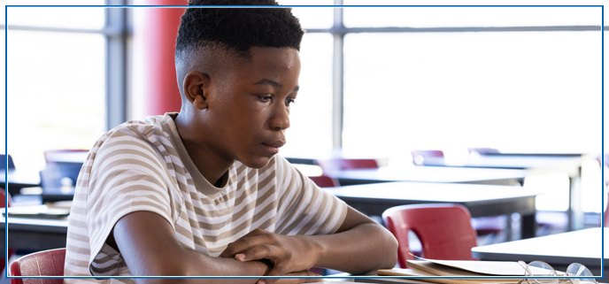 Boy sitting at a desk studying from his notebook.