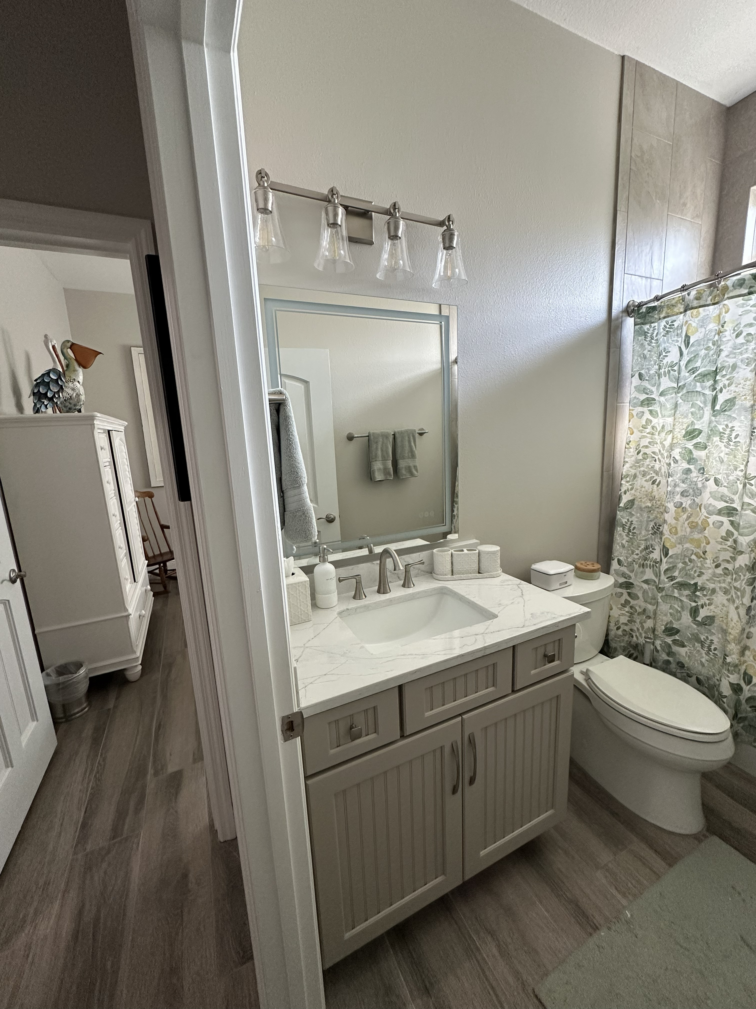 Elegant bathroom featuring semi-custom painted beadboard cabinetry, Pompeii quartz countertops, satin nickel hardware, and fixtures.