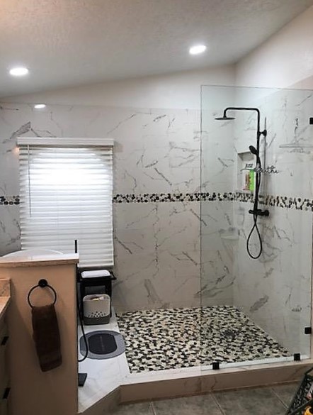 Large walk-in shower featuring shaved salt & pepper pebbles, glossy Statuario shower walls, and a matching pebble band.